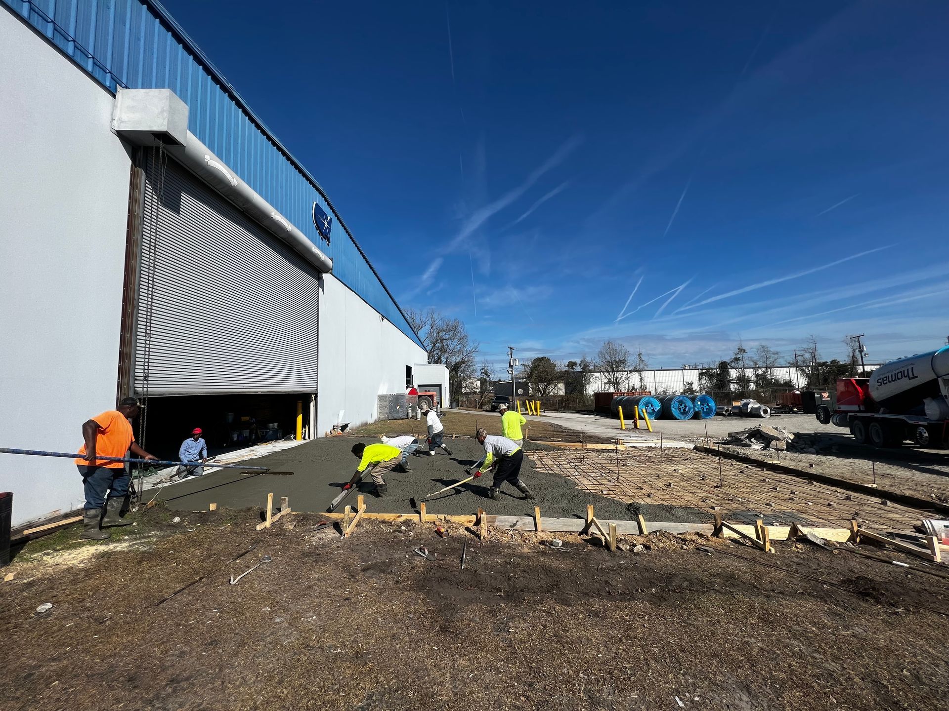 A group of construction workers are working on a sidewalk in front of a building.