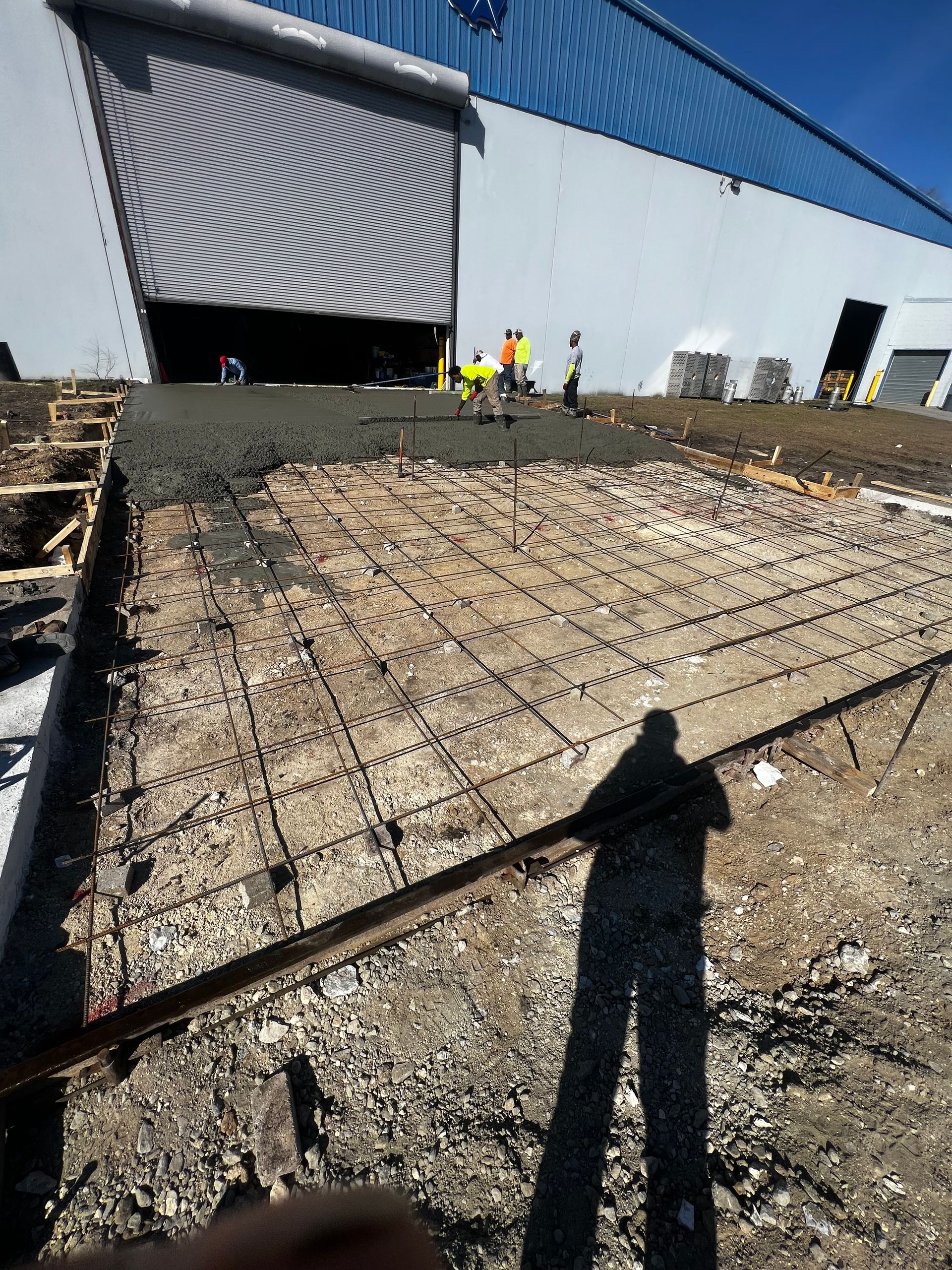 A shadow of a person is cast on the ground in front of a building.