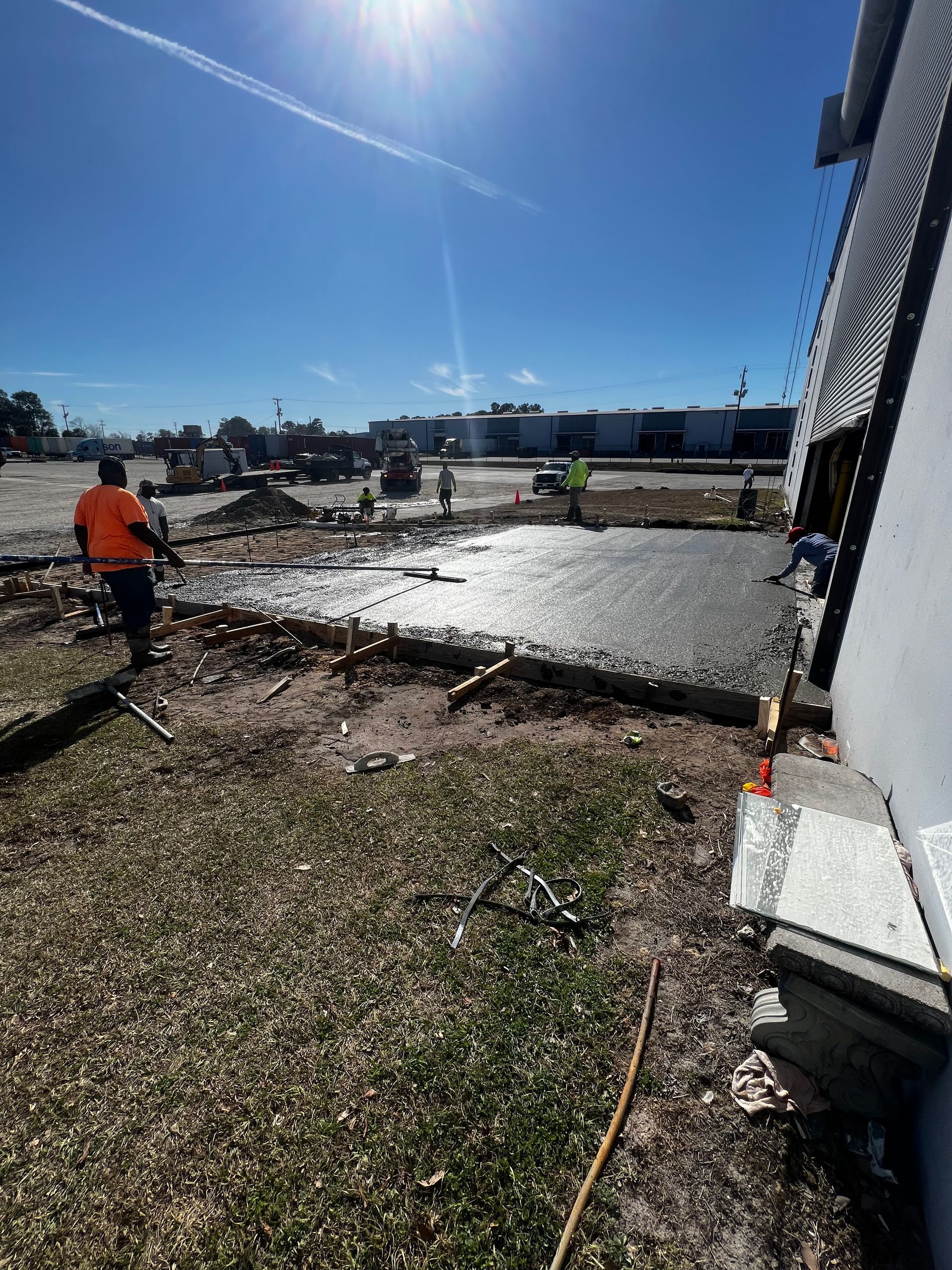 A group of construction workers are working on a concrete driveway.