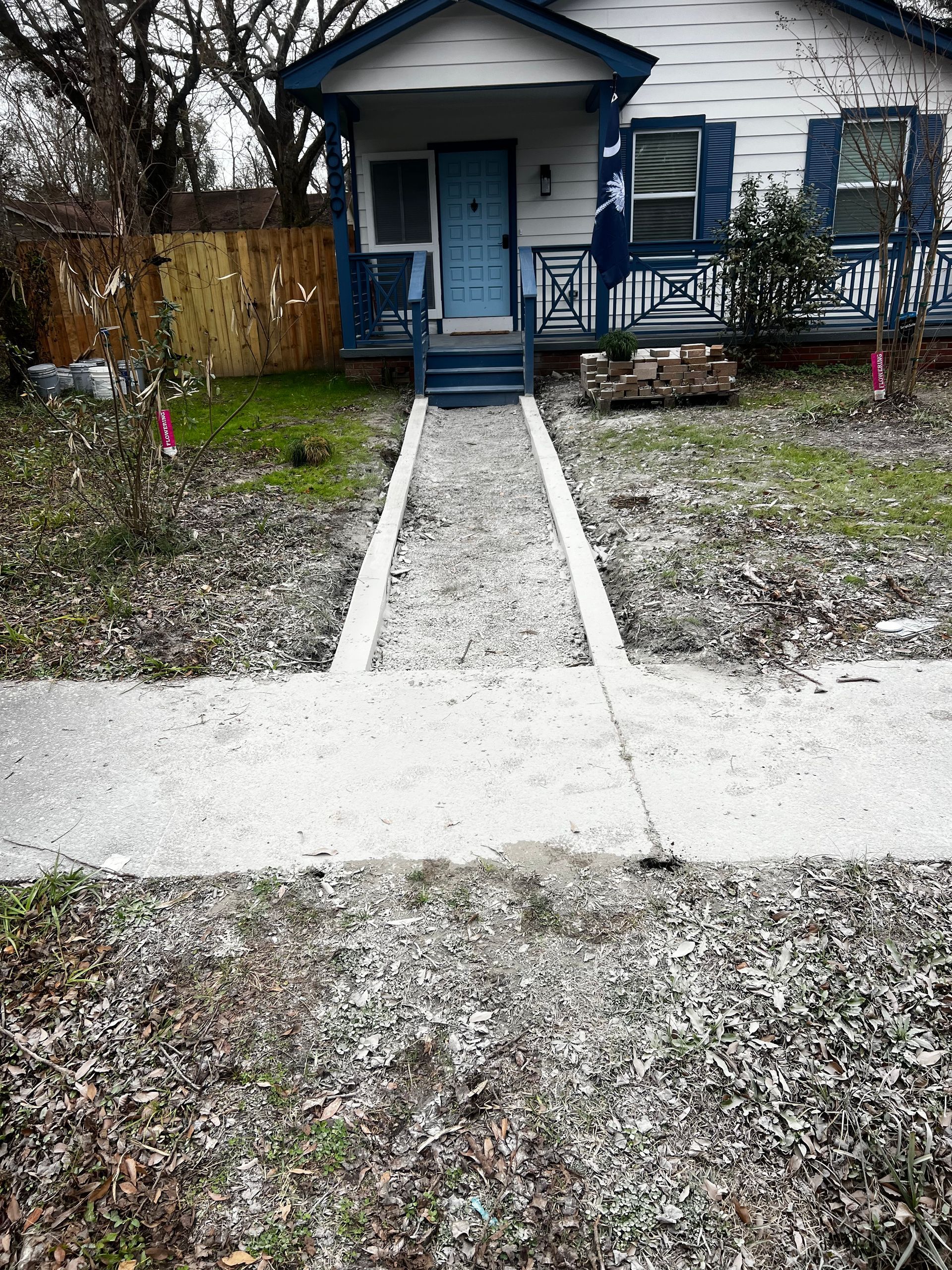 A white house with a blue door and a walkway leading to it