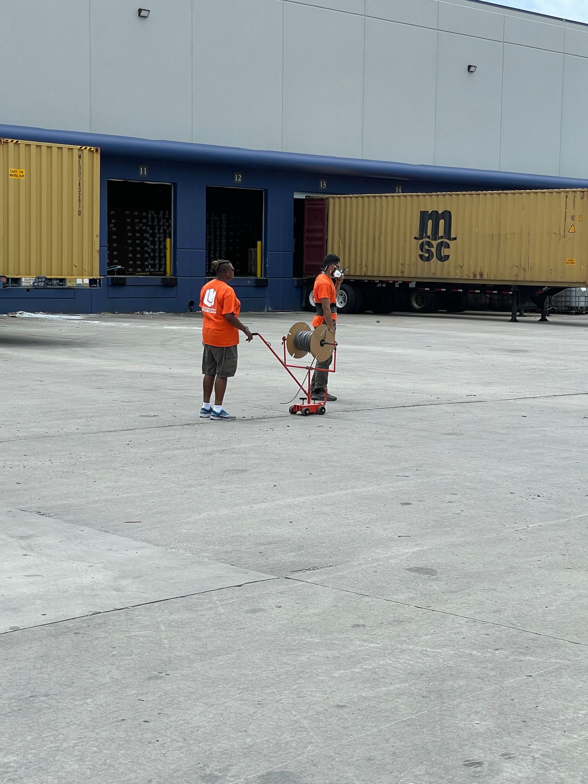 Two men are pulling a box in front of a msc truck