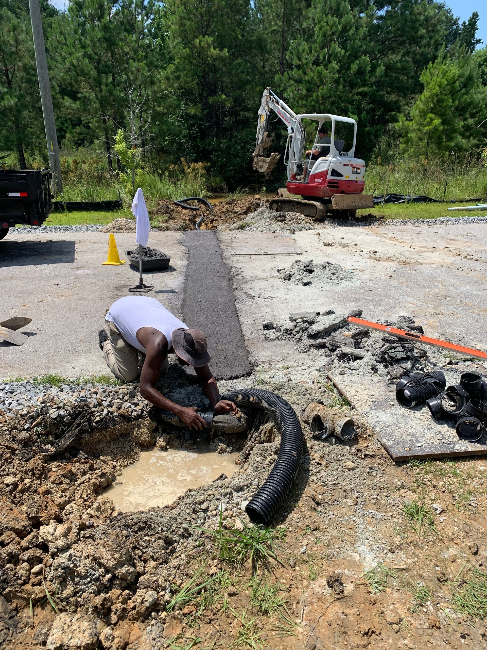 A man is kneeling in the dirt next to a bulldozer.