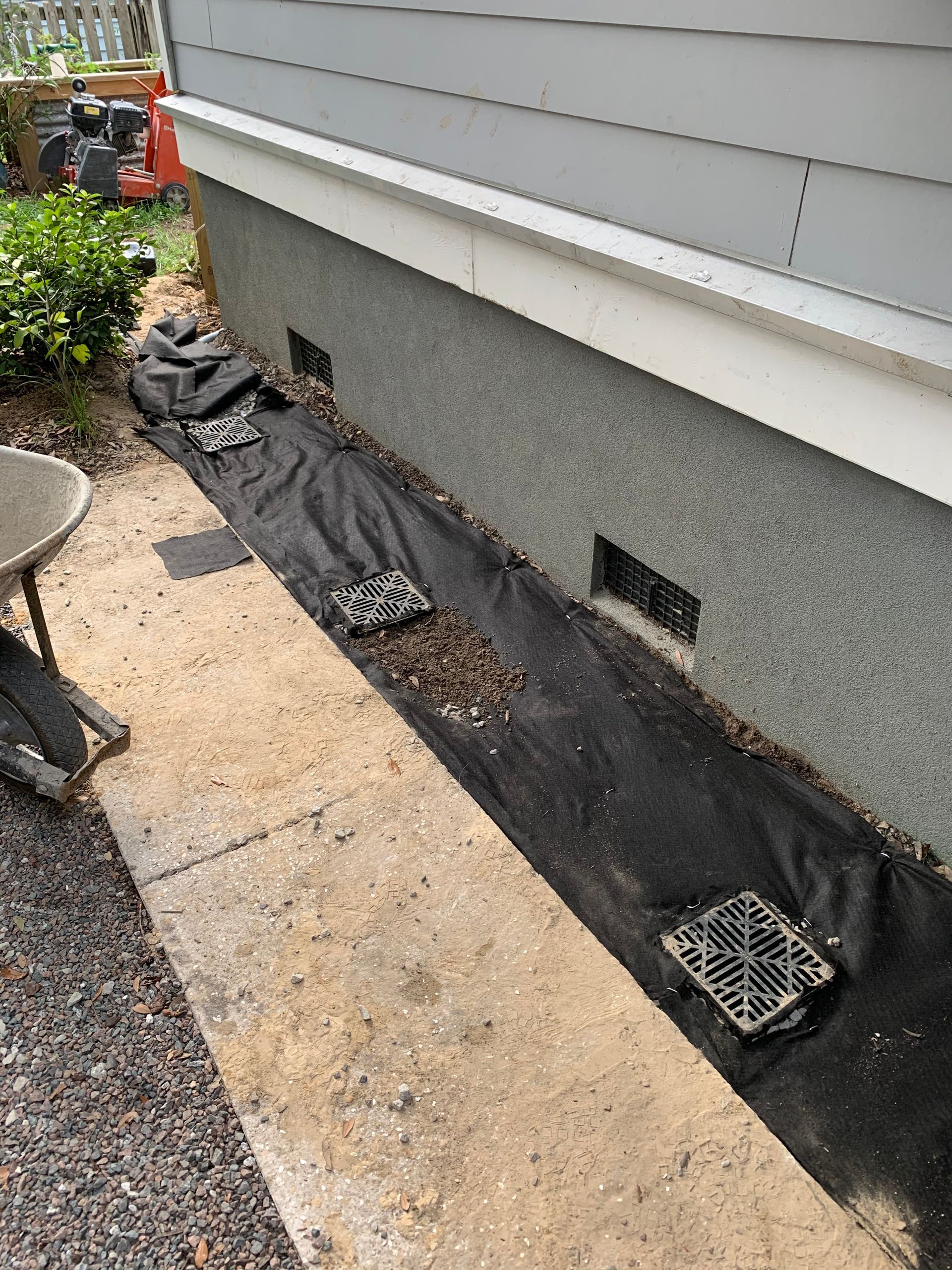A drainage system is being installed on the side of a house.