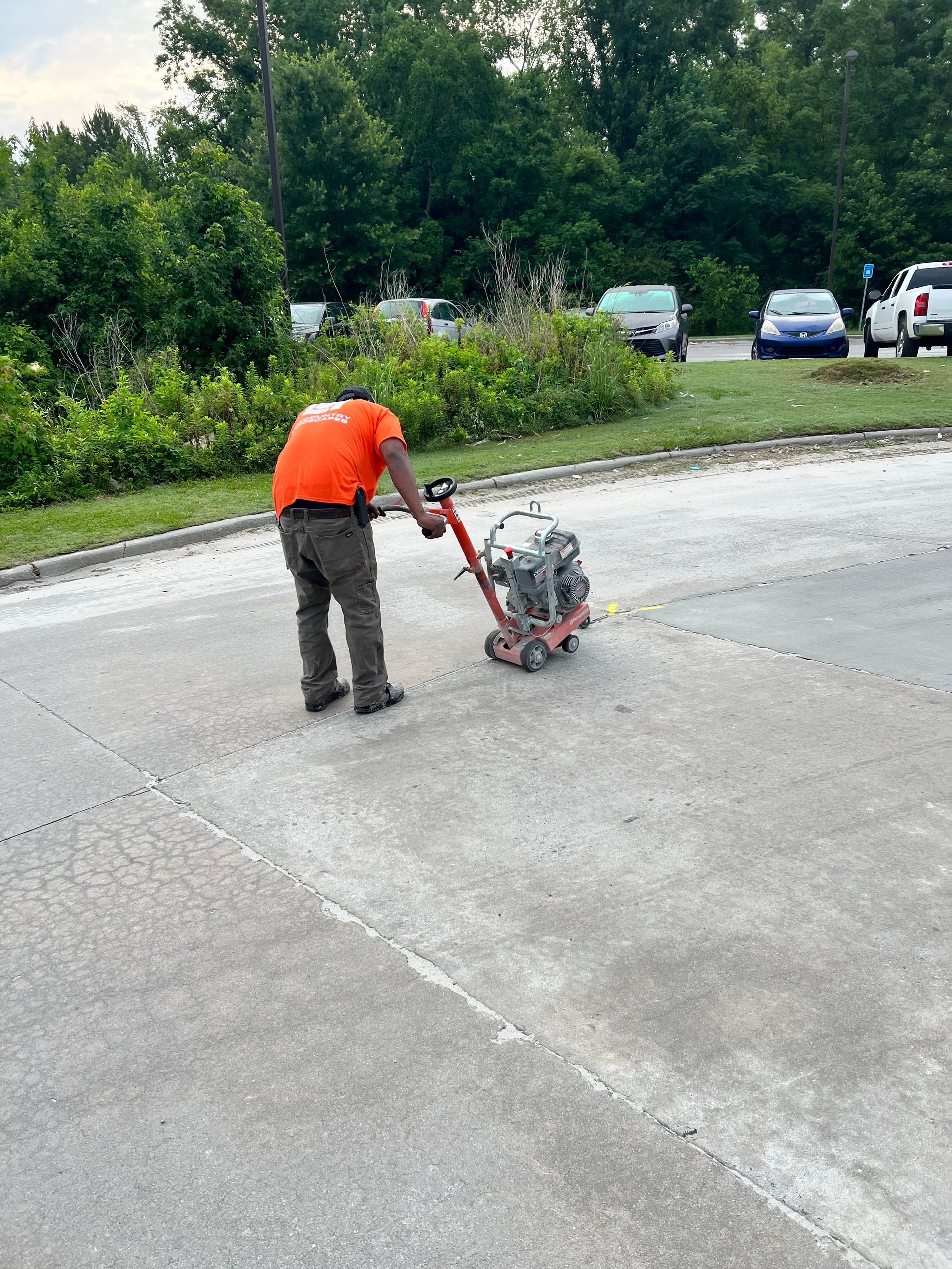 A man is using a vacuum cleaner to clean a concrete driveway.