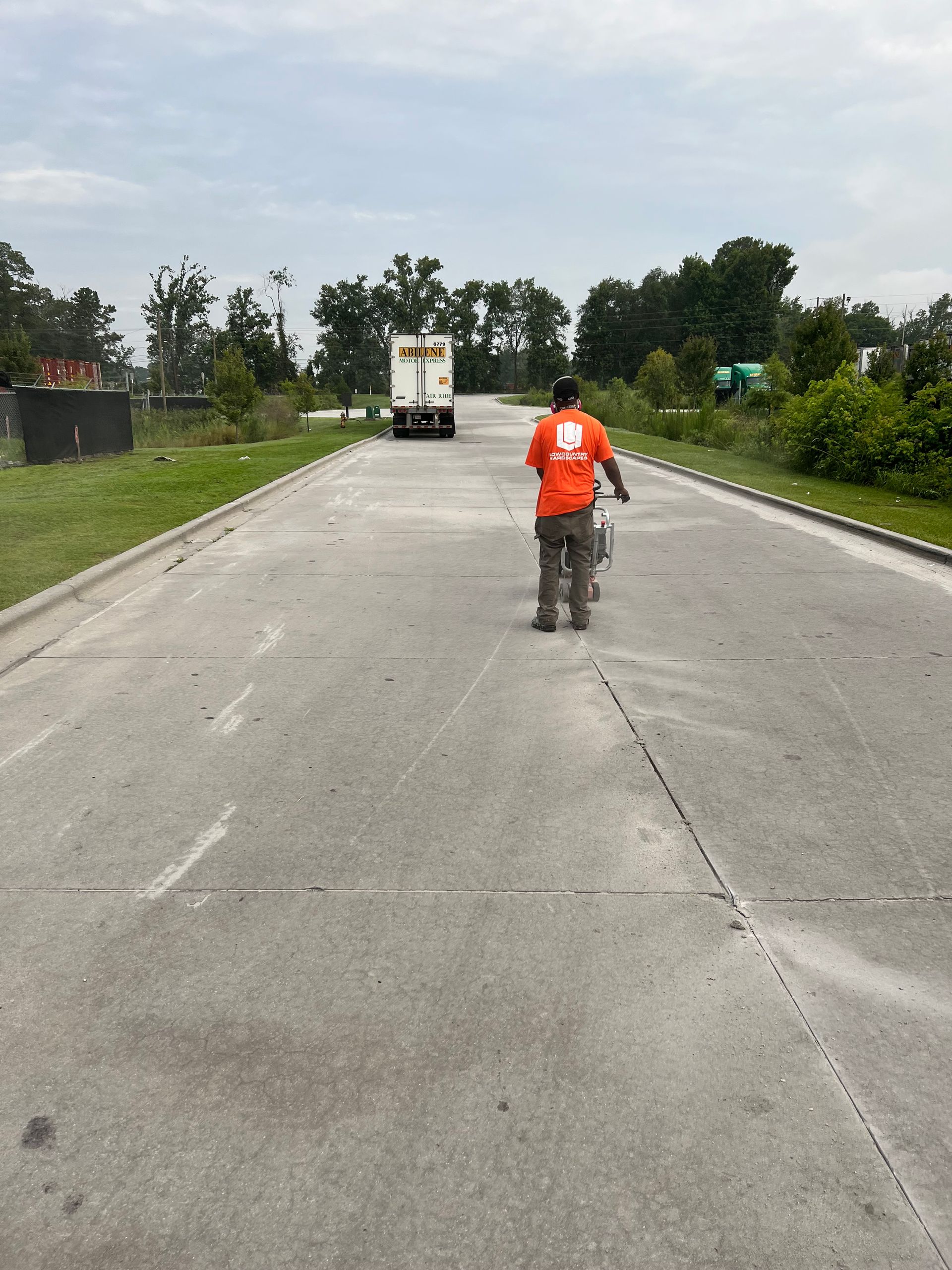 A man in an orange shirt is walking down a road