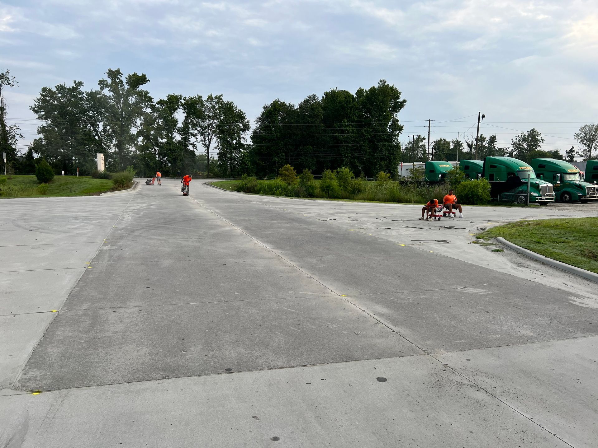A row of green semi trucks are parked on the side of the road