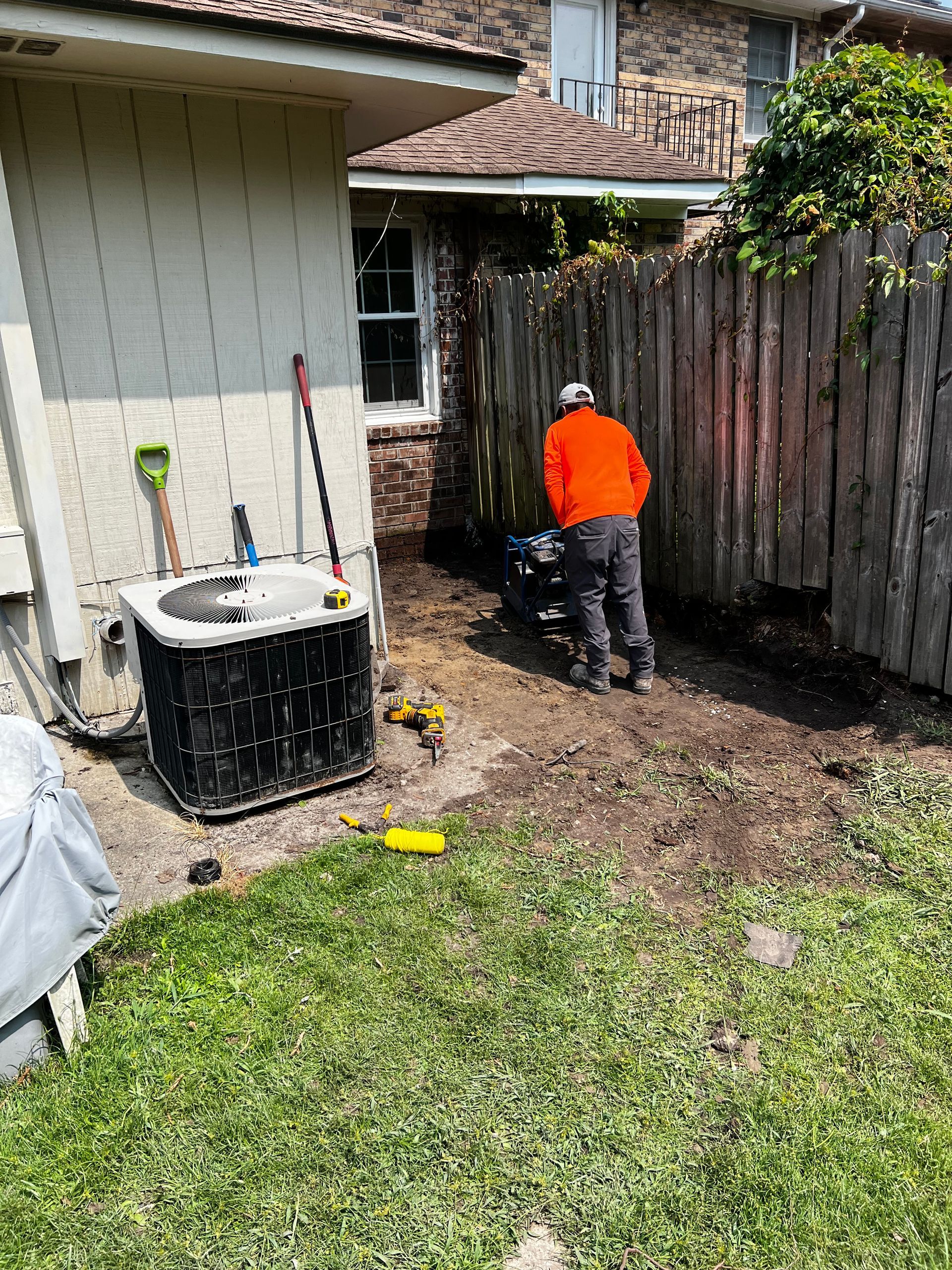 A man is standing in the dirt in front of a house.