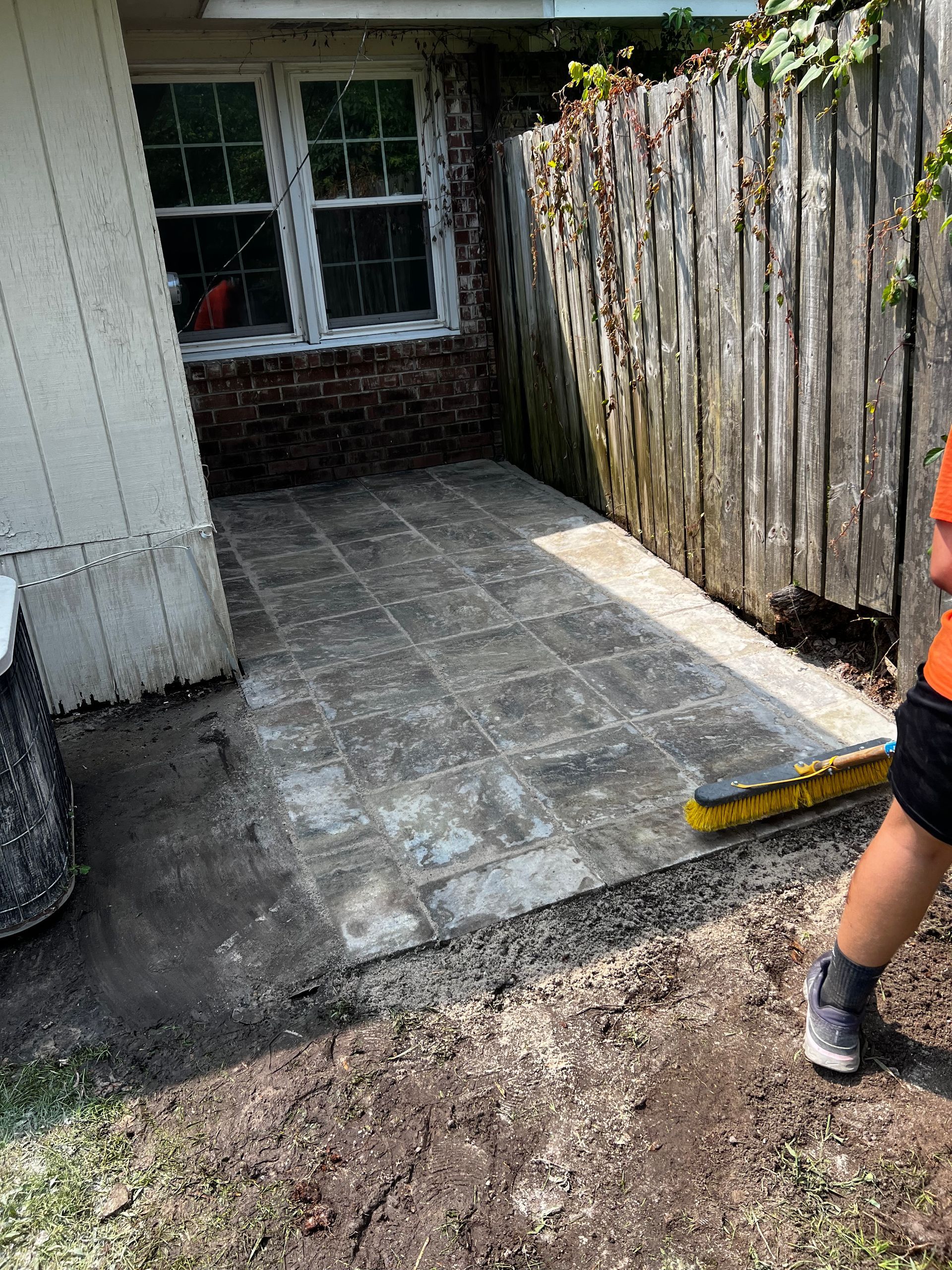 A person is standing in the dirt next to a wooden fence.