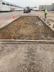 A man is working on a concrete slab in a parking lot.