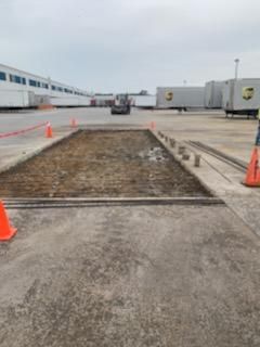 A man is standing in a parking lot next to orange cones.