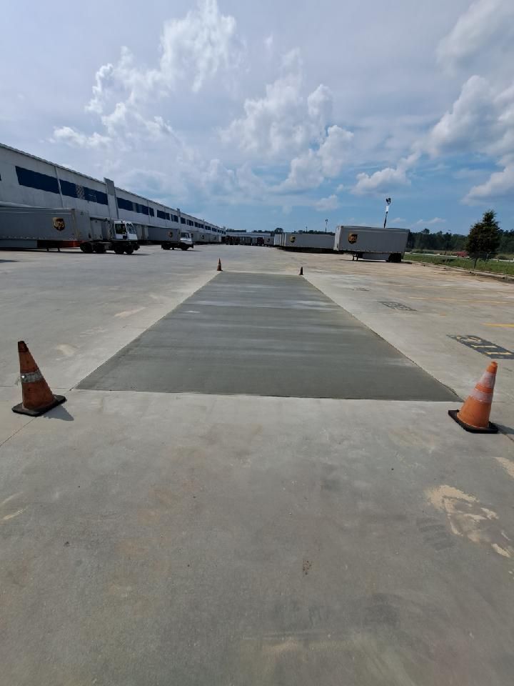 A parking lot with a lot of trucks and cones in front of a building.