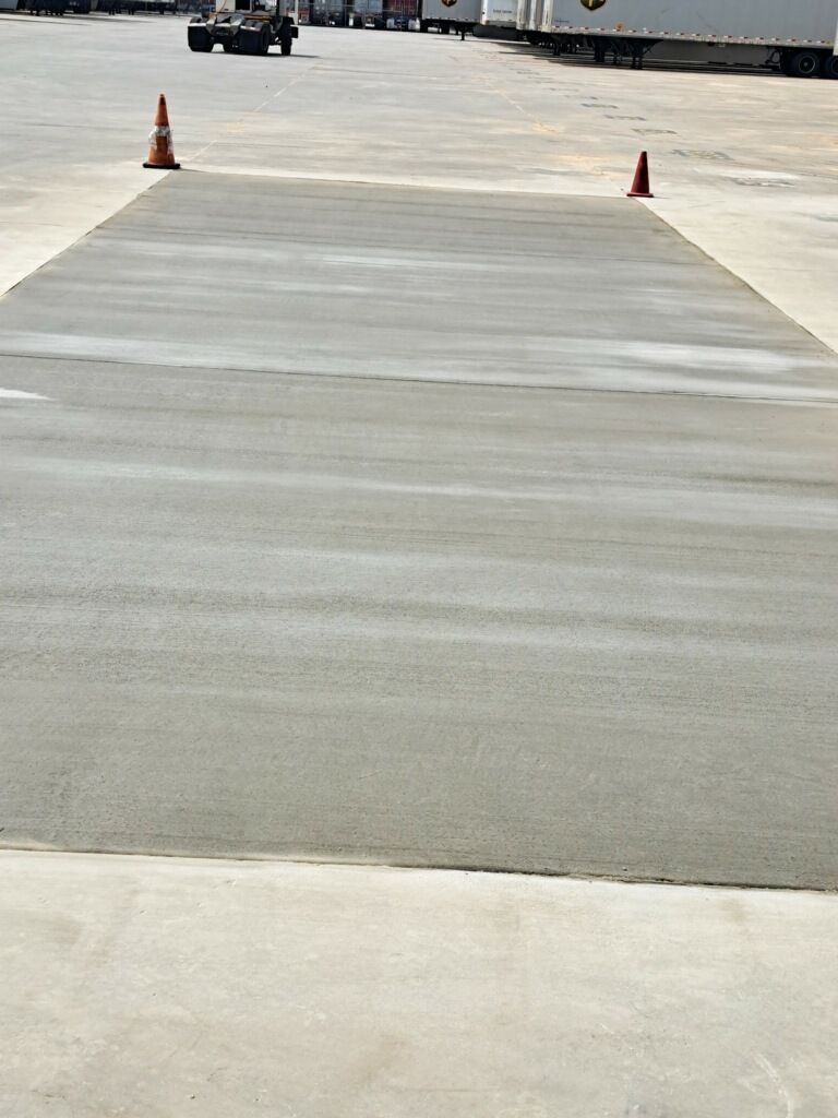 A concrete parking lot with trucks and cones on it