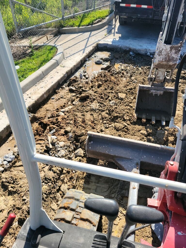 A red excavator is digging a hole in the ground.