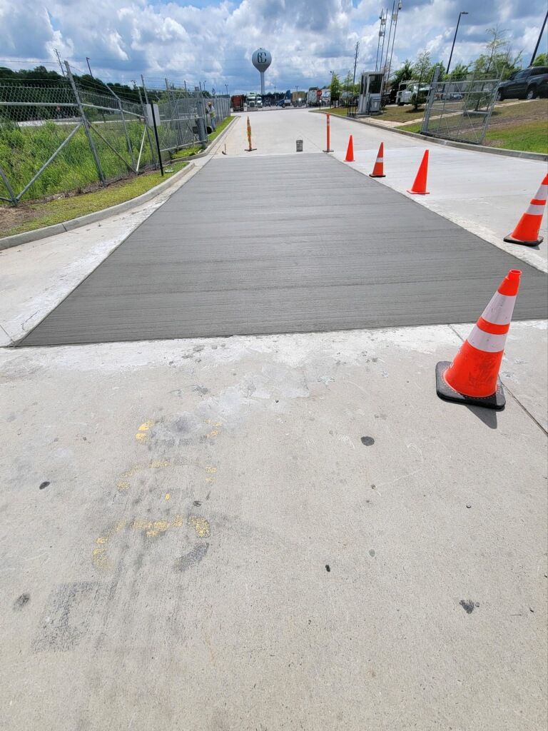A concrete road with orange traffic cones on the side of it.