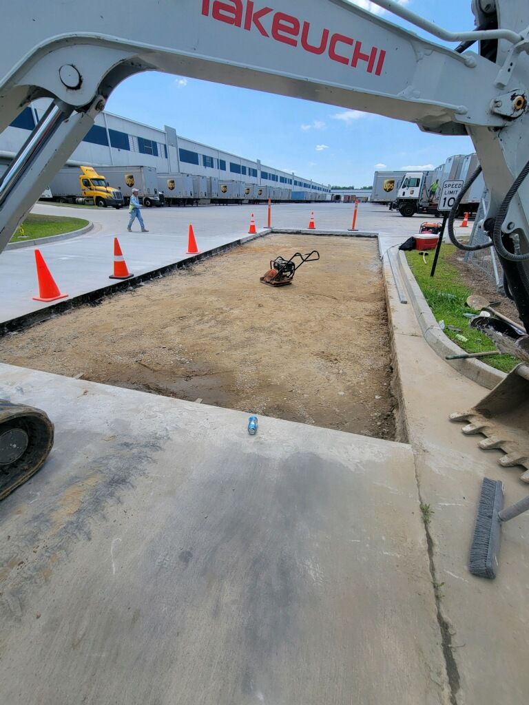 A takeuchi excavator is digging a hole in a parking lot.