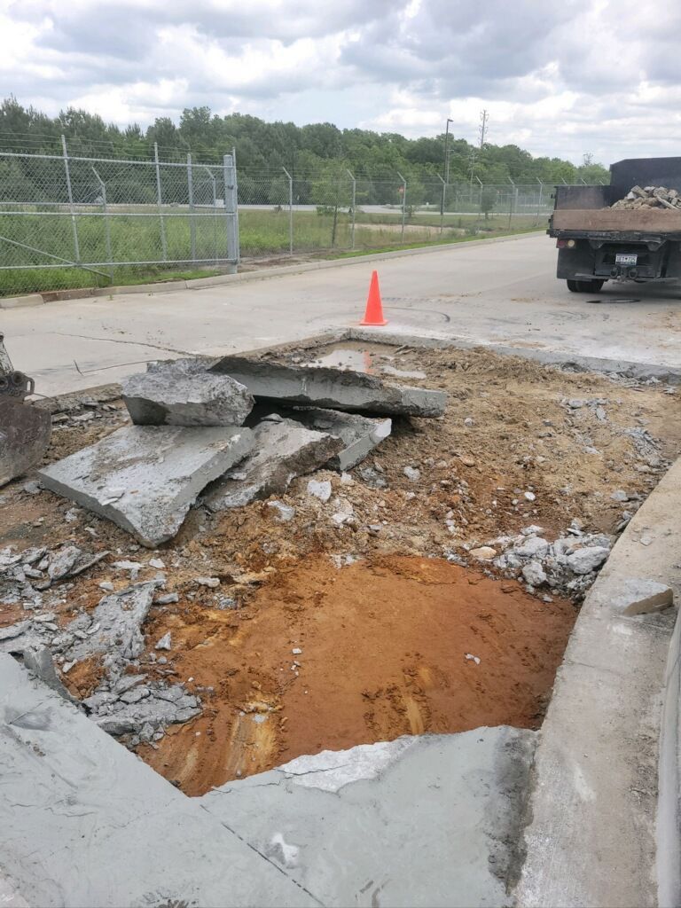 A truck is parked on the side of the road next to a hole in the ground.