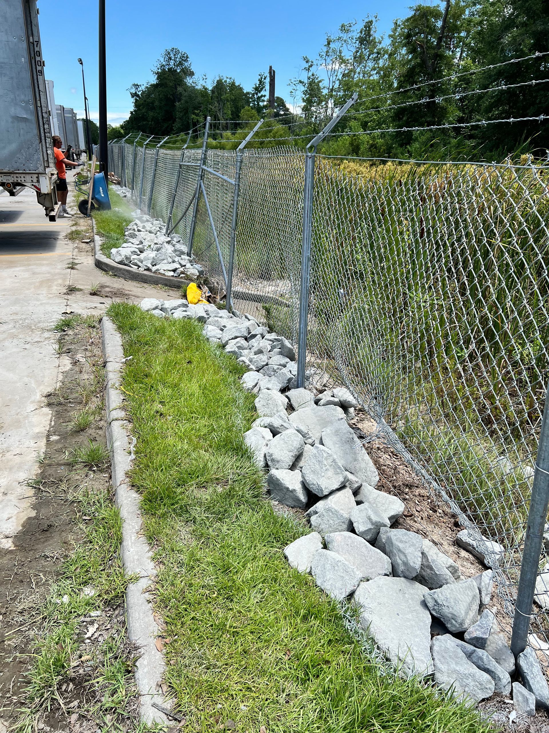 A chain link fence is being built next to a grassy area.