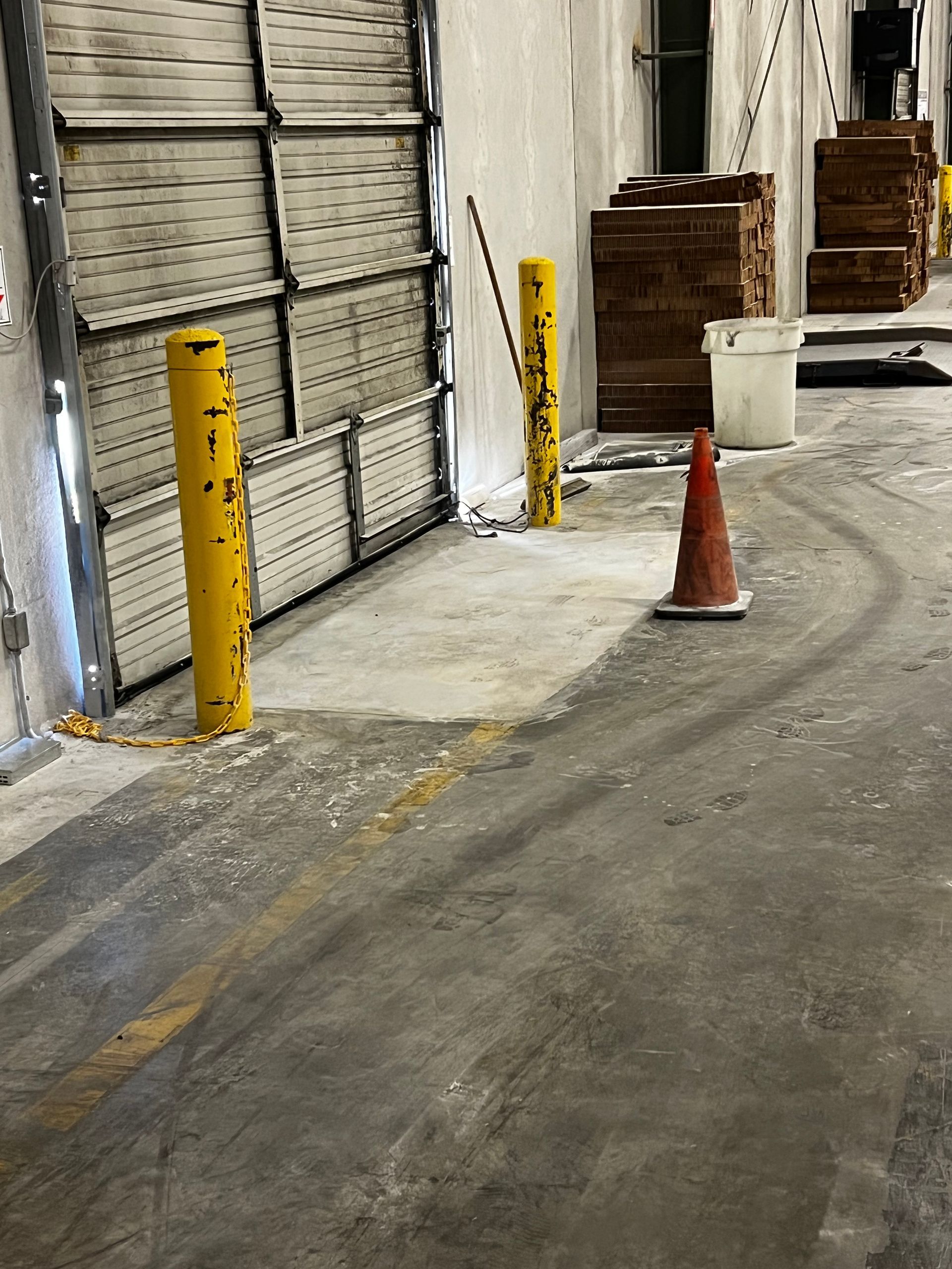 A warehouse with yellow poles and a red cone