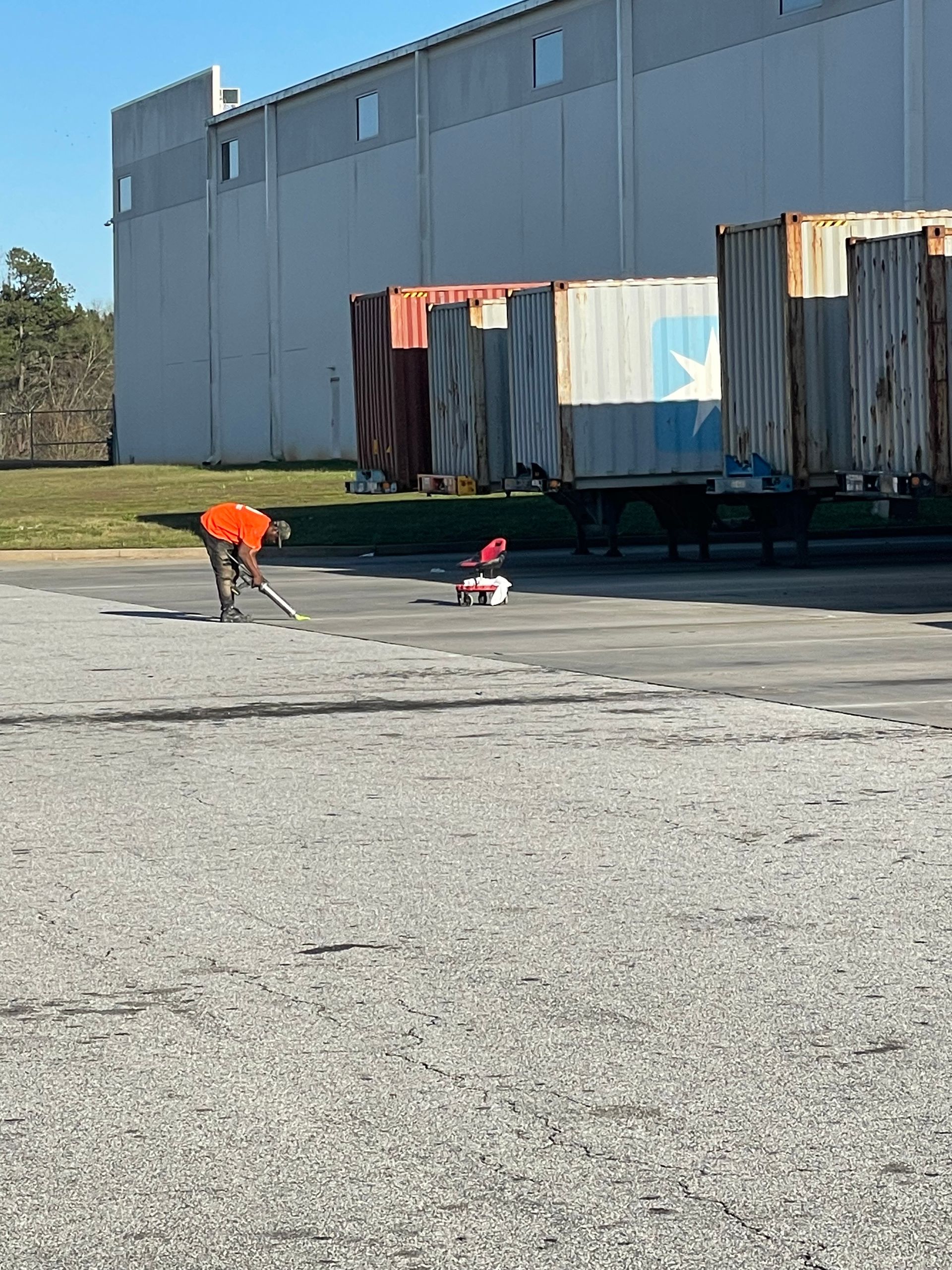 A man is kneeling down in front of a row of shipping containers