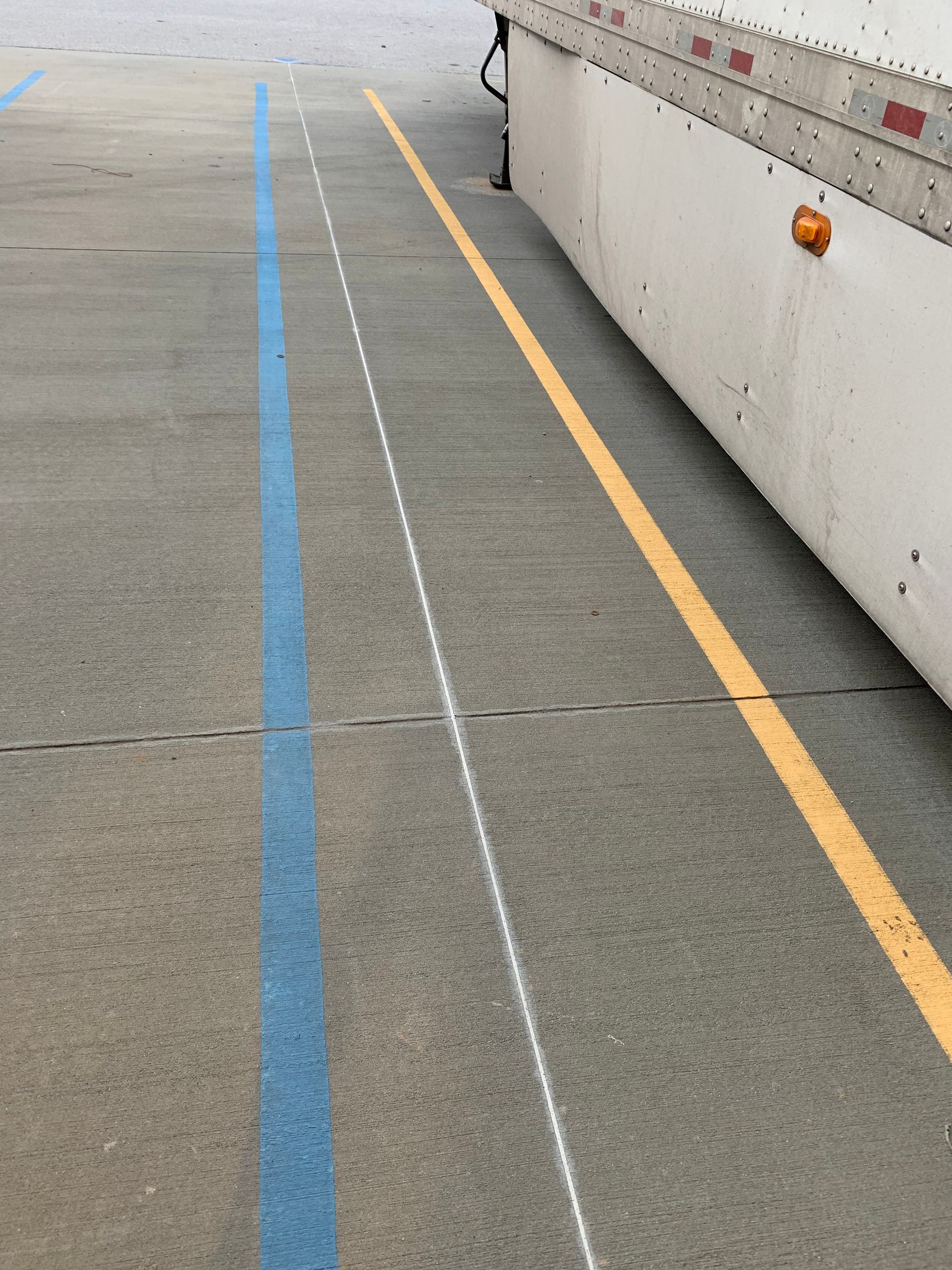 A white truck is parked next to a blue line on the road