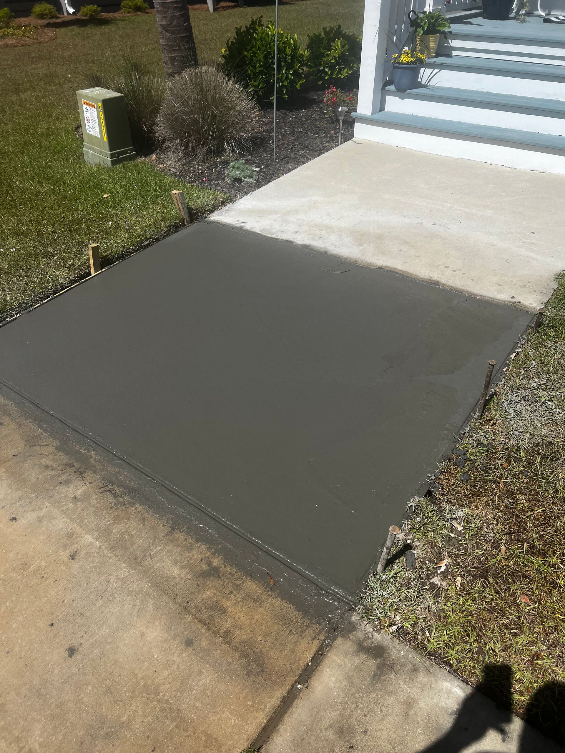 A concrete walkway is being built in front of a house.