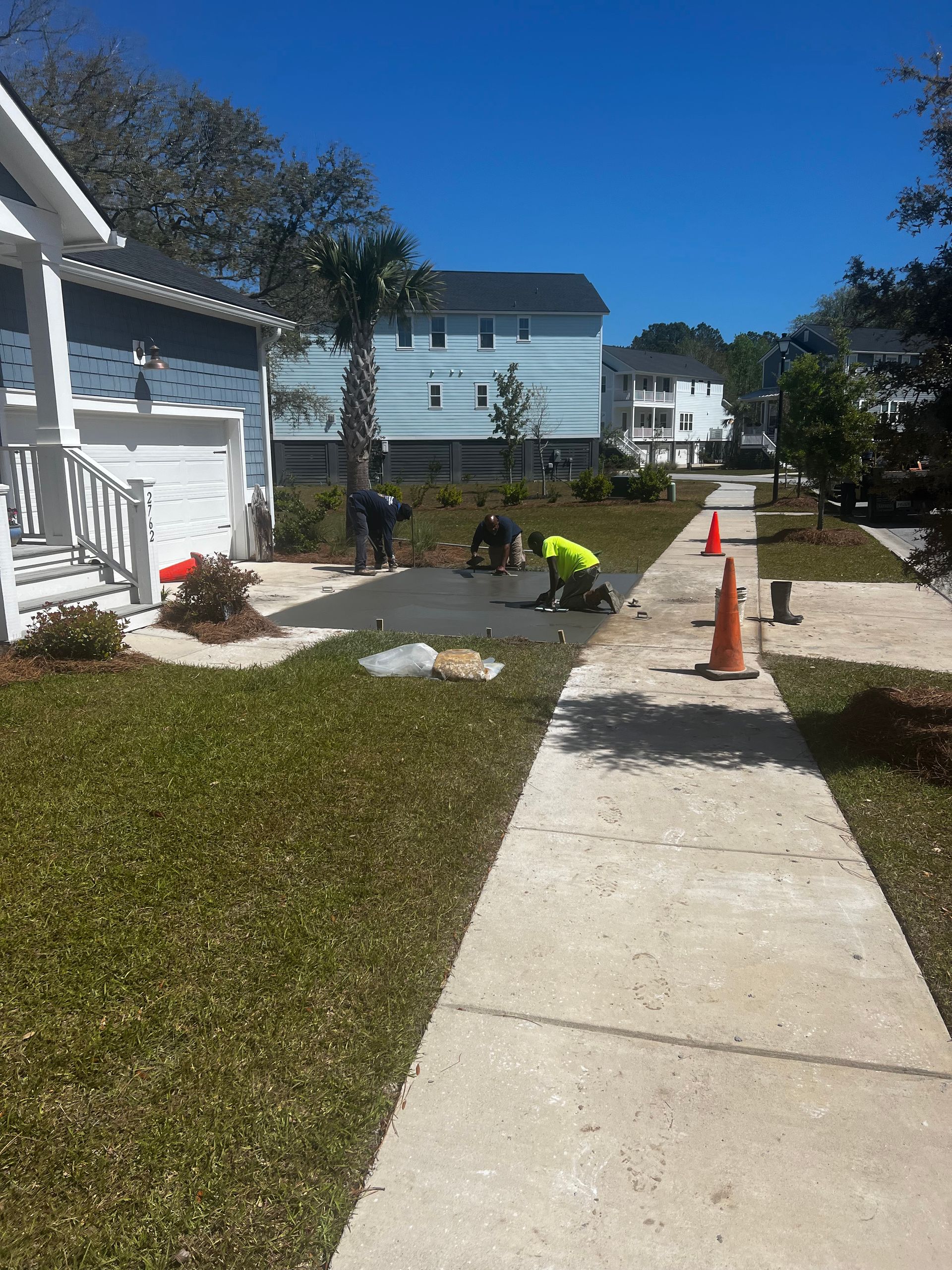 A man is working on a sidewalk in front of a house.