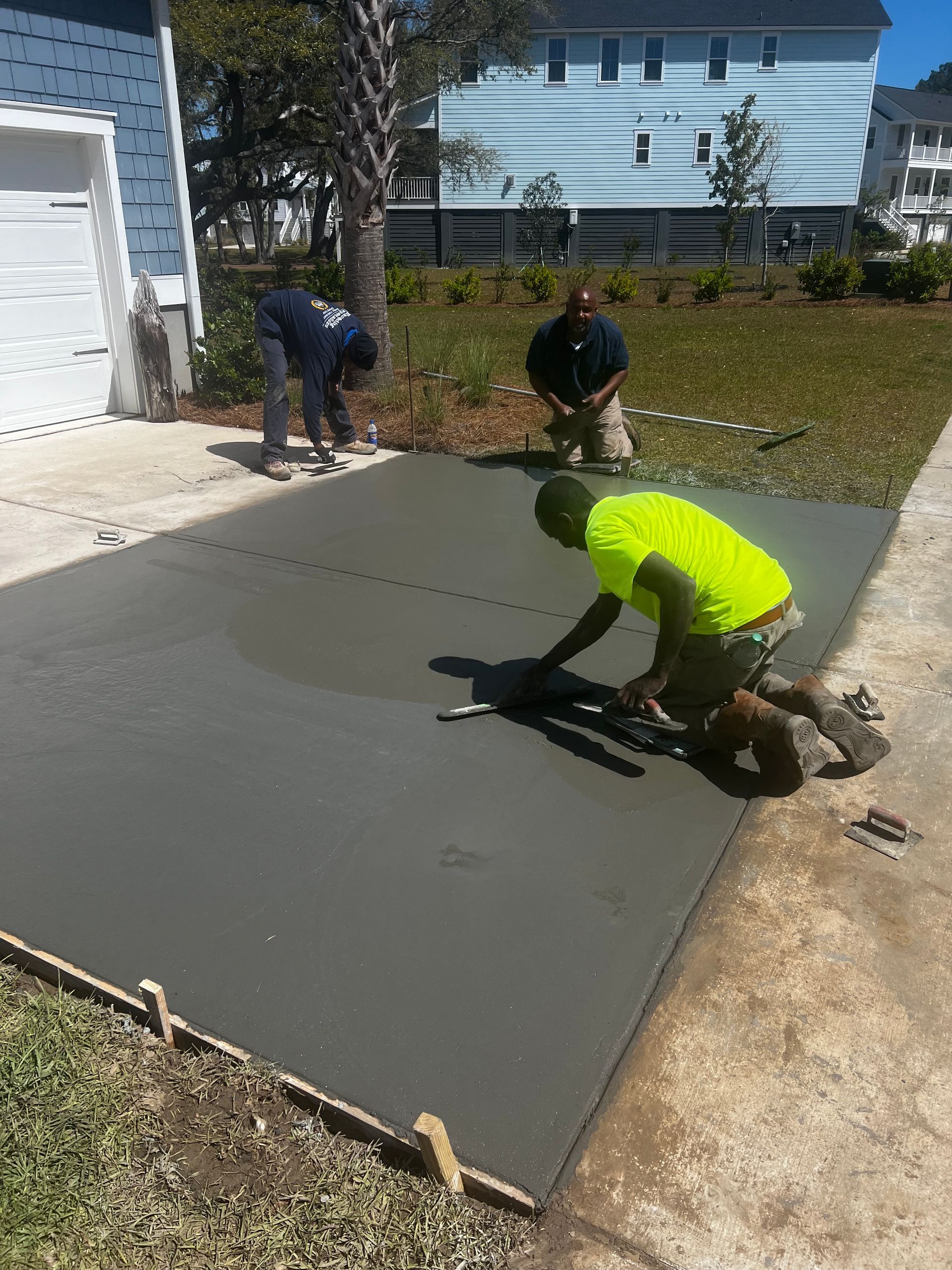 A group of men are working on a concrete driveway.