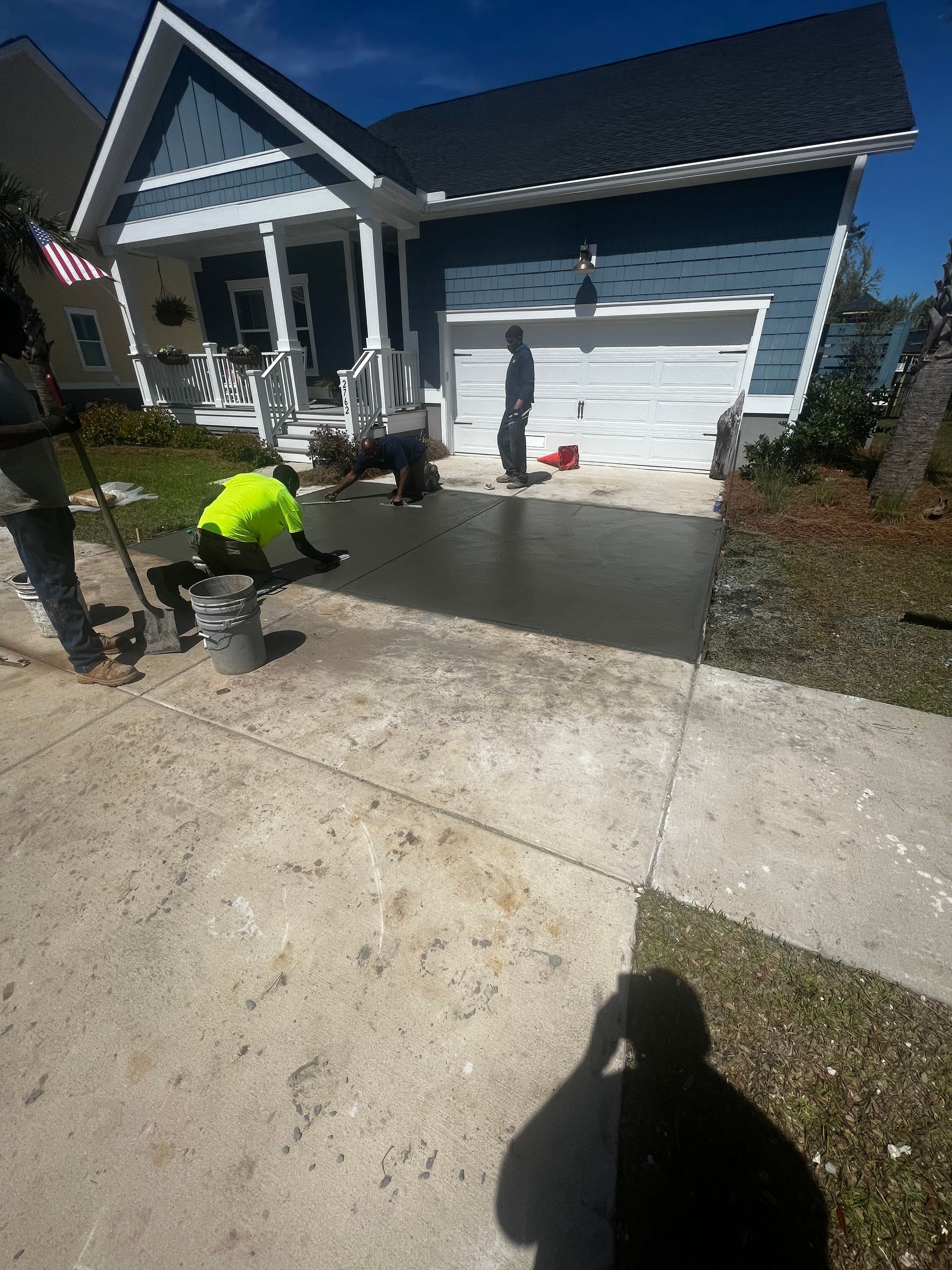 A man is laying concrete in front of a house.
