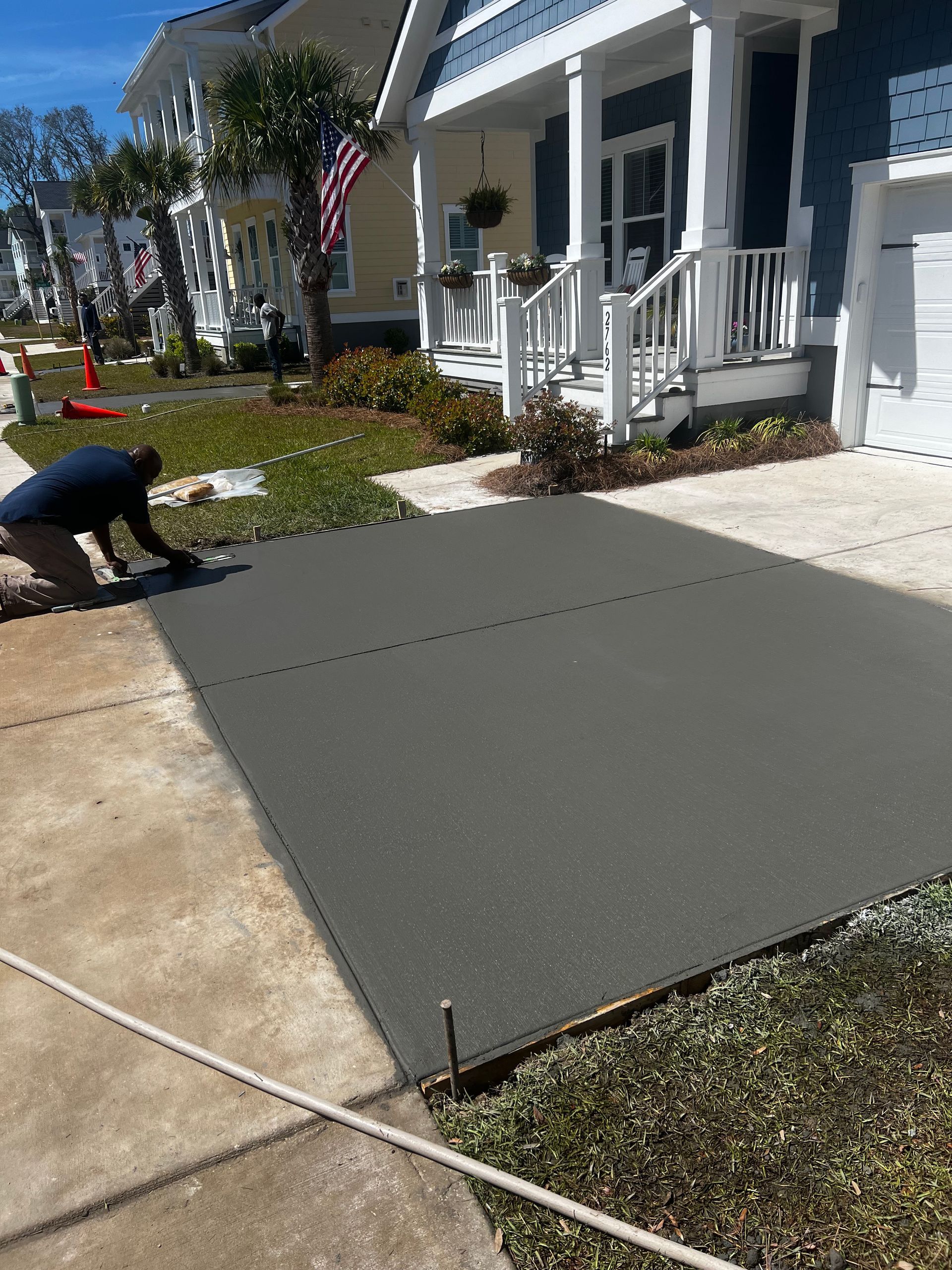 A man is working on a concrete driveway in front of a house.