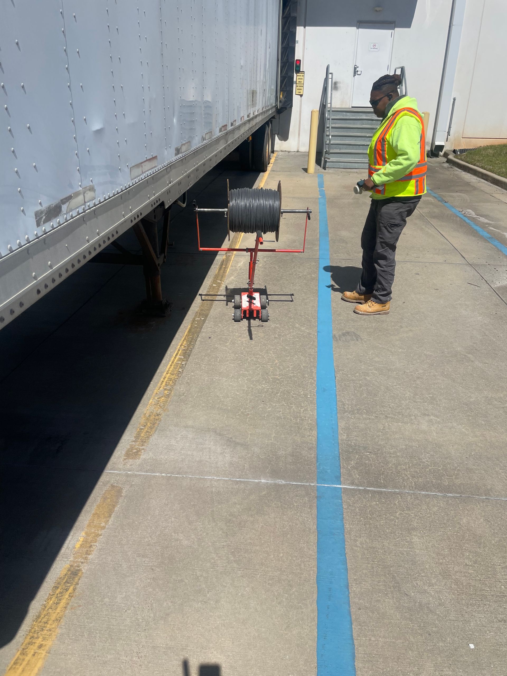 A man in a safety vest is standing next to a truck in a parking lot.