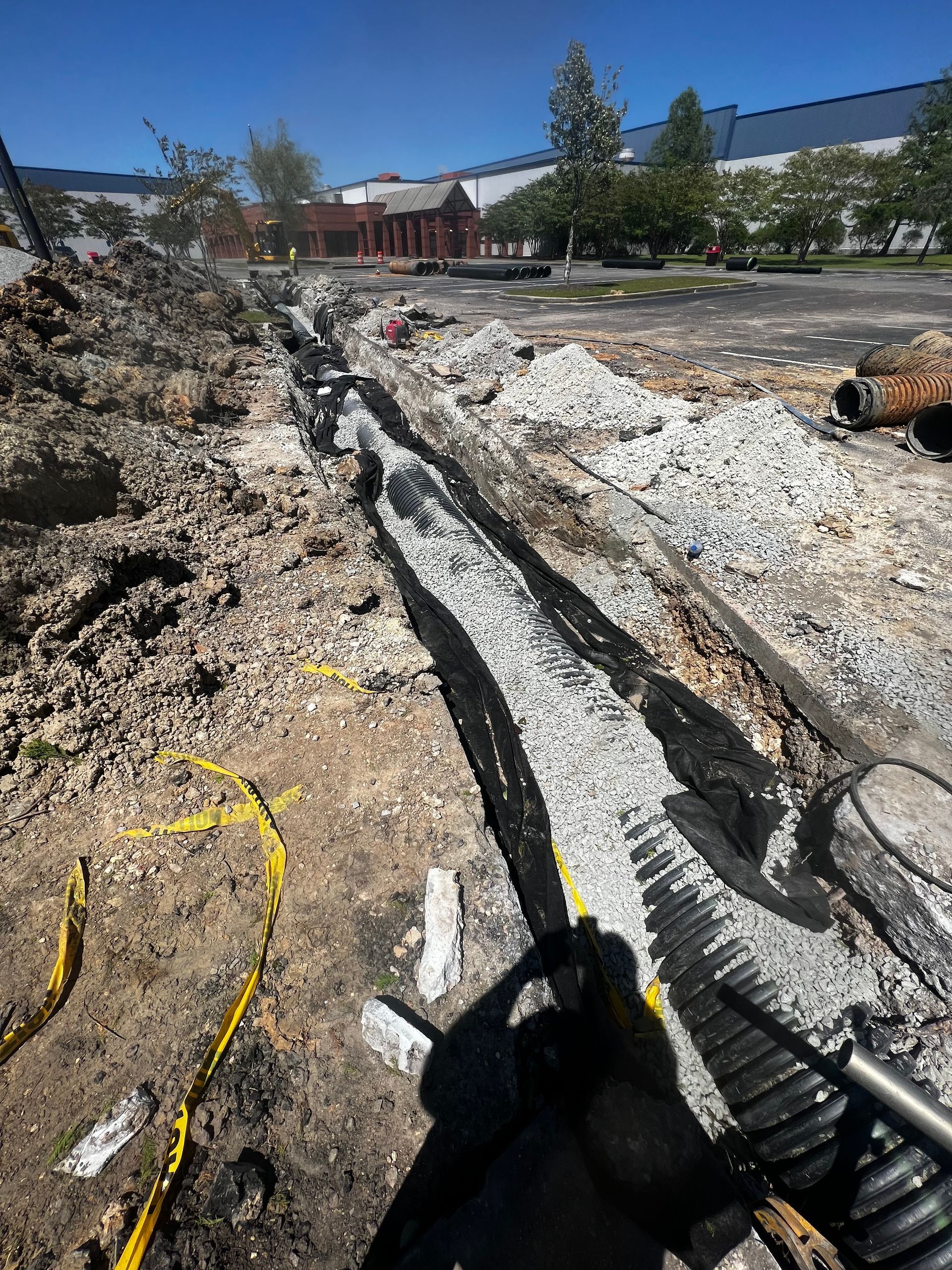 A person is standing in the dirt next to a pipe.