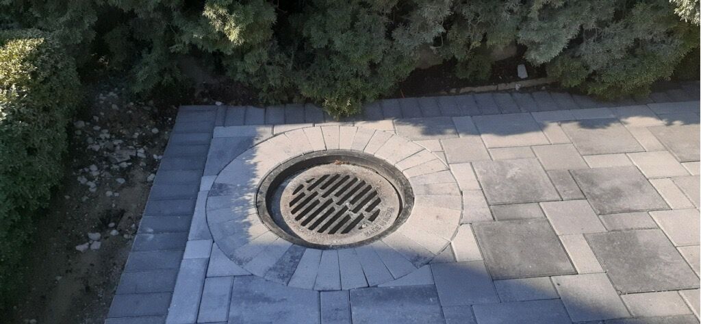 A manhole cover is sitting on top of a brick walkway.