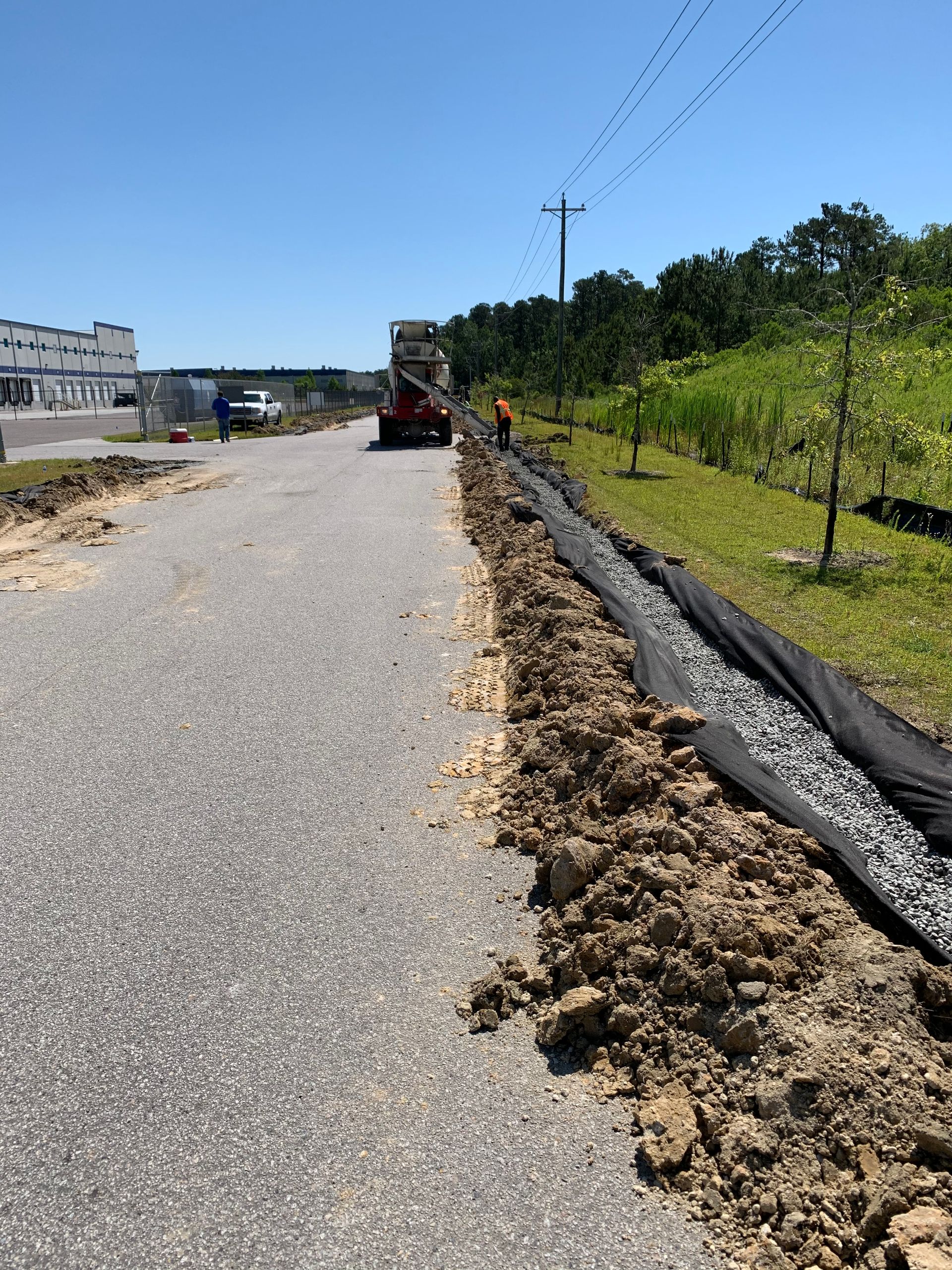 A truck is driving down a road next to a pile of dirt.