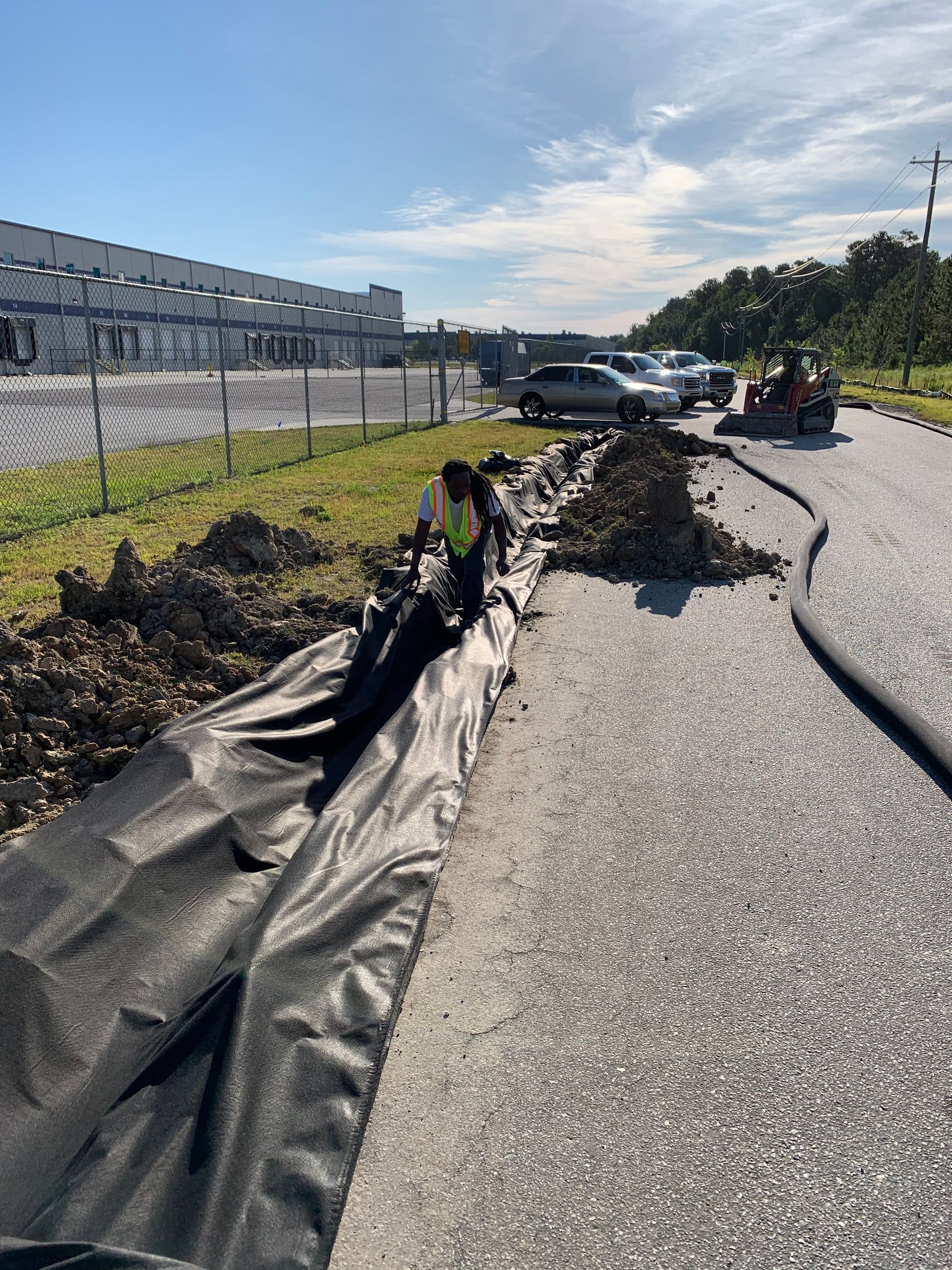 A man is working on a gravel road next to a building.
