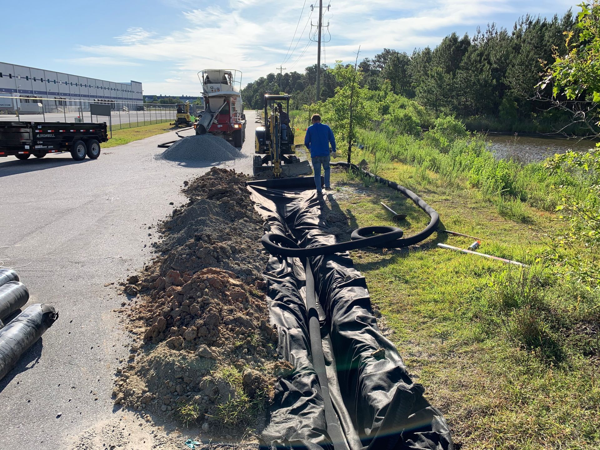 A man is standing next to a machine that is digging a hole in the ground.