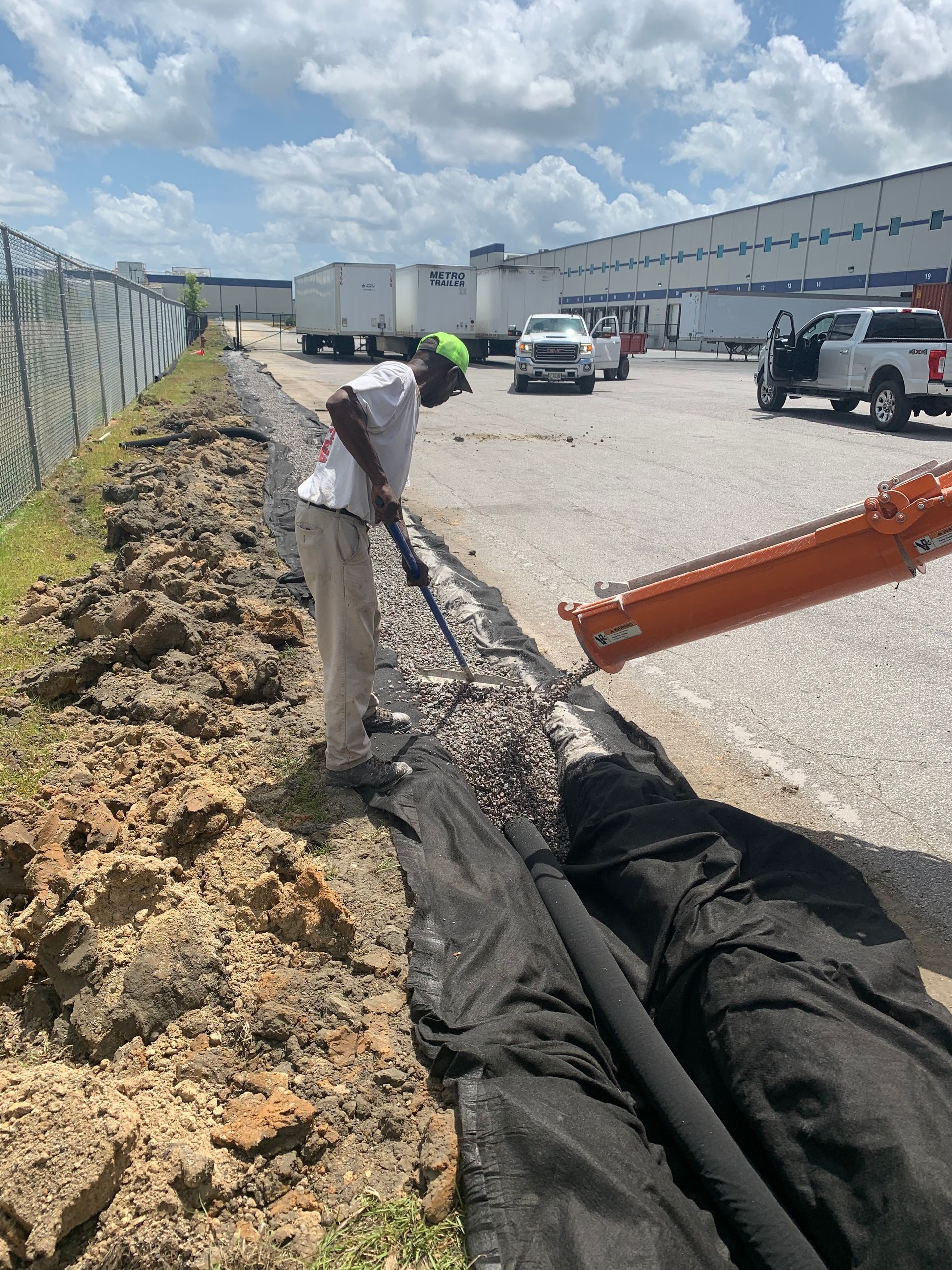 A man is digging in the dirt with a shovel in a parking lot.