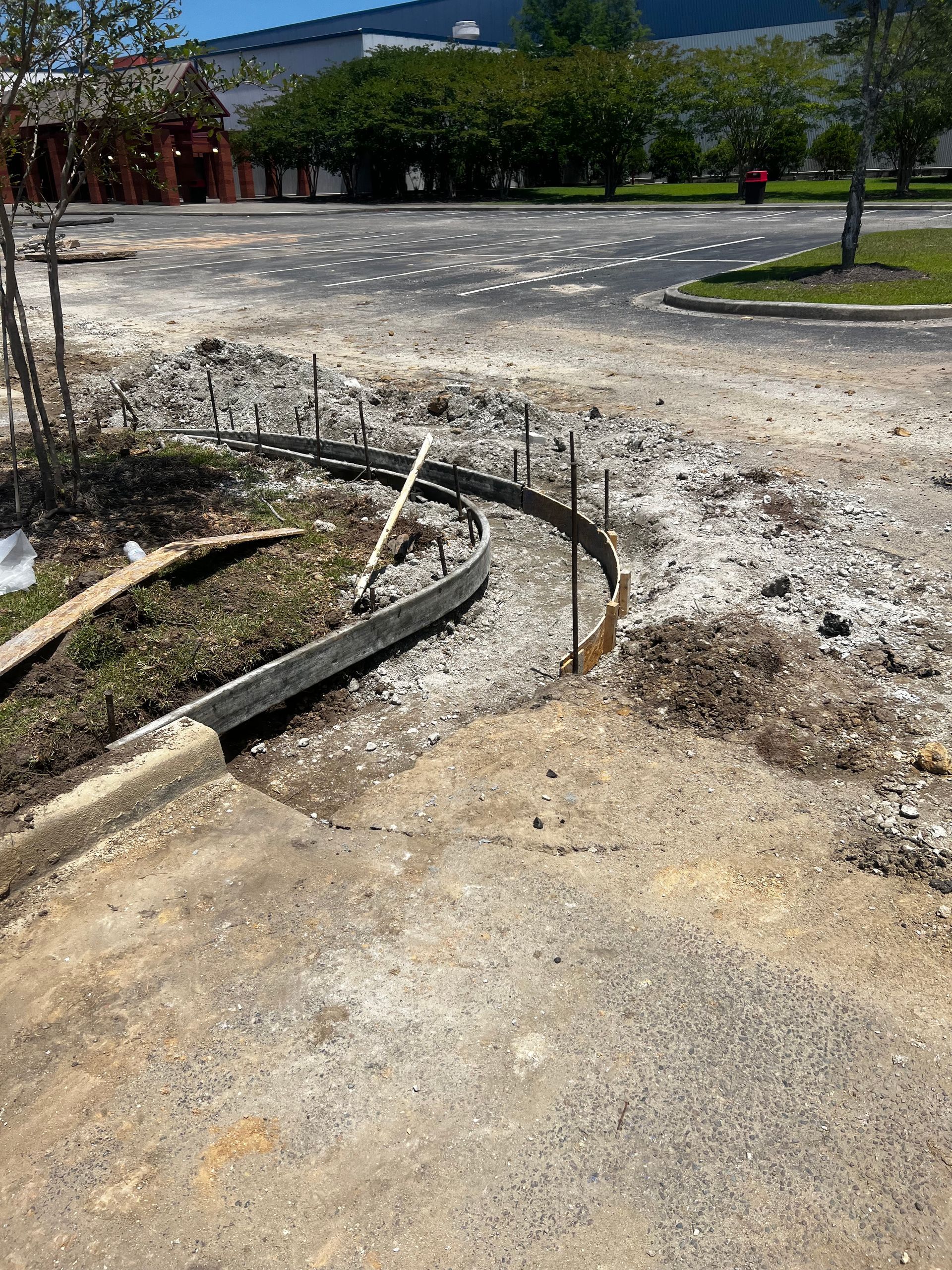 A concrete curb is being installed in a parking lot.