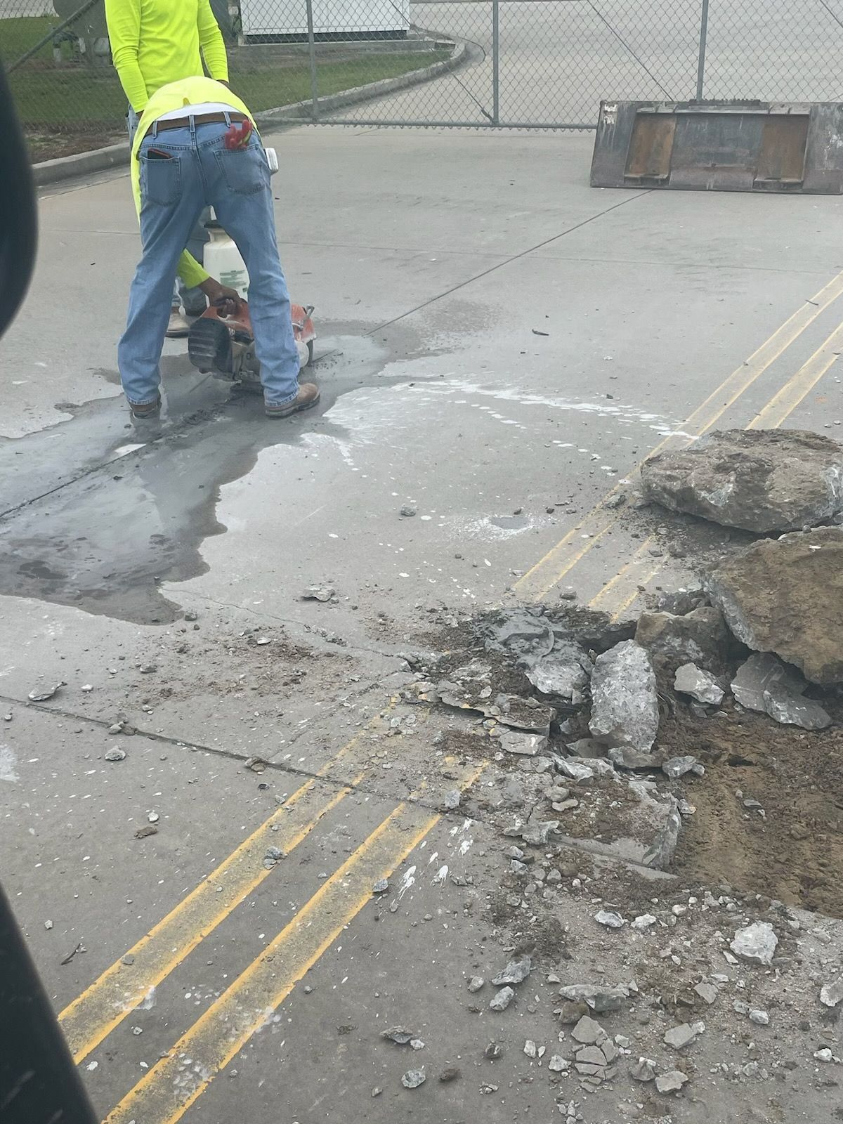 A man is using a concrete saw to cut a hole in the ground