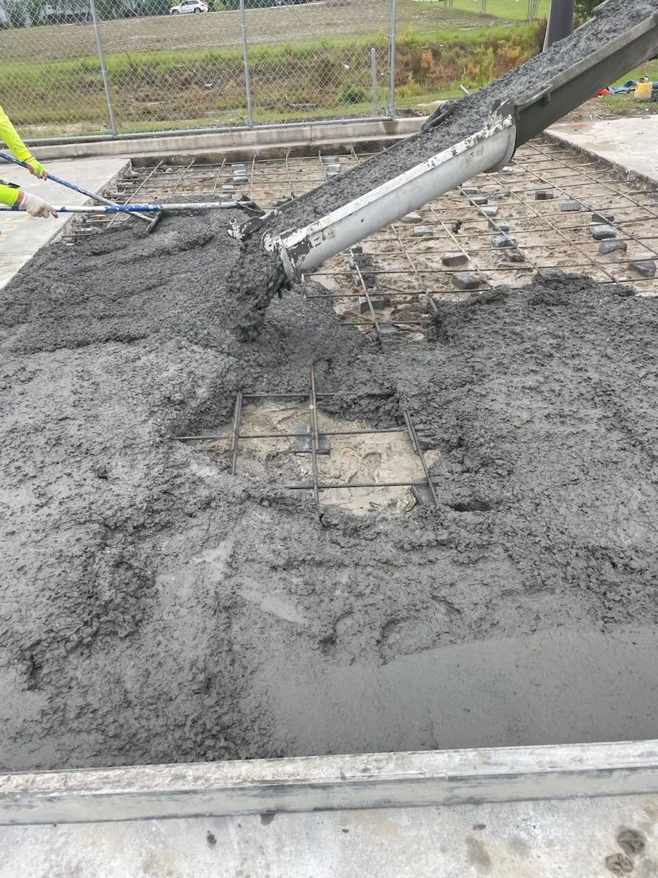 A person is pouring concrete into a hole in the ground.