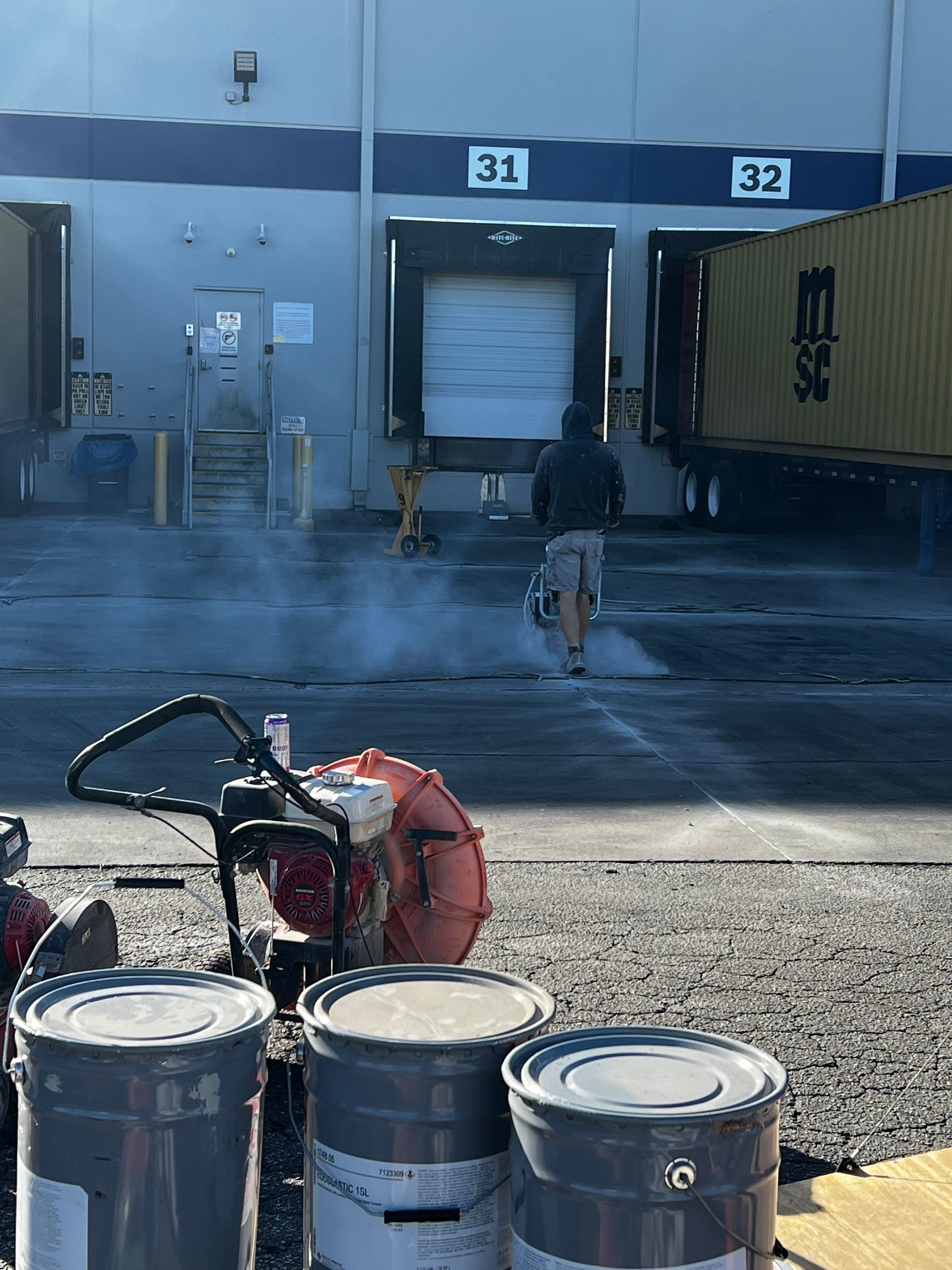 A man is riding a motorcycle in front of a warehouse.