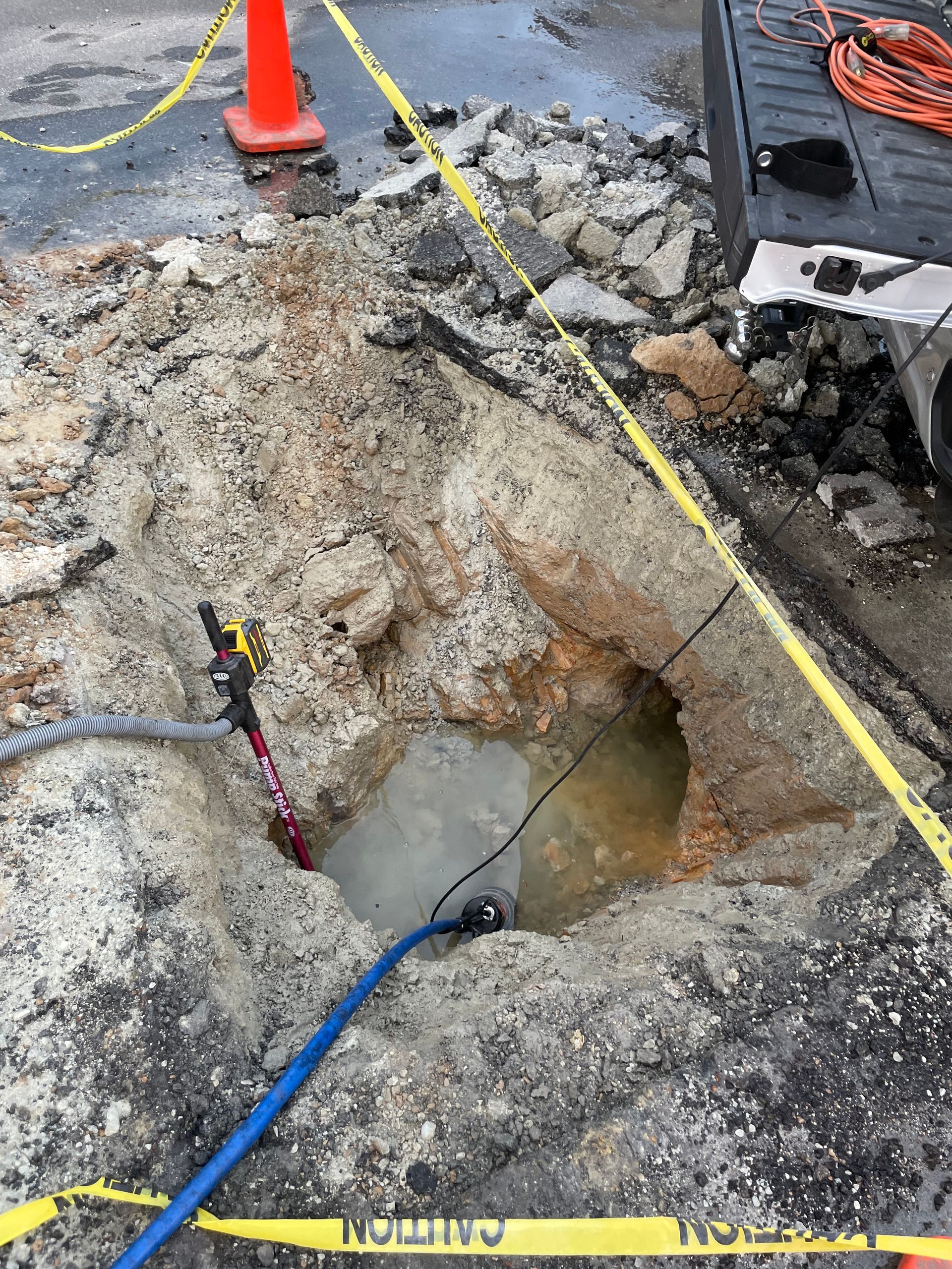 A hole in the ground with a hose coming out of it.