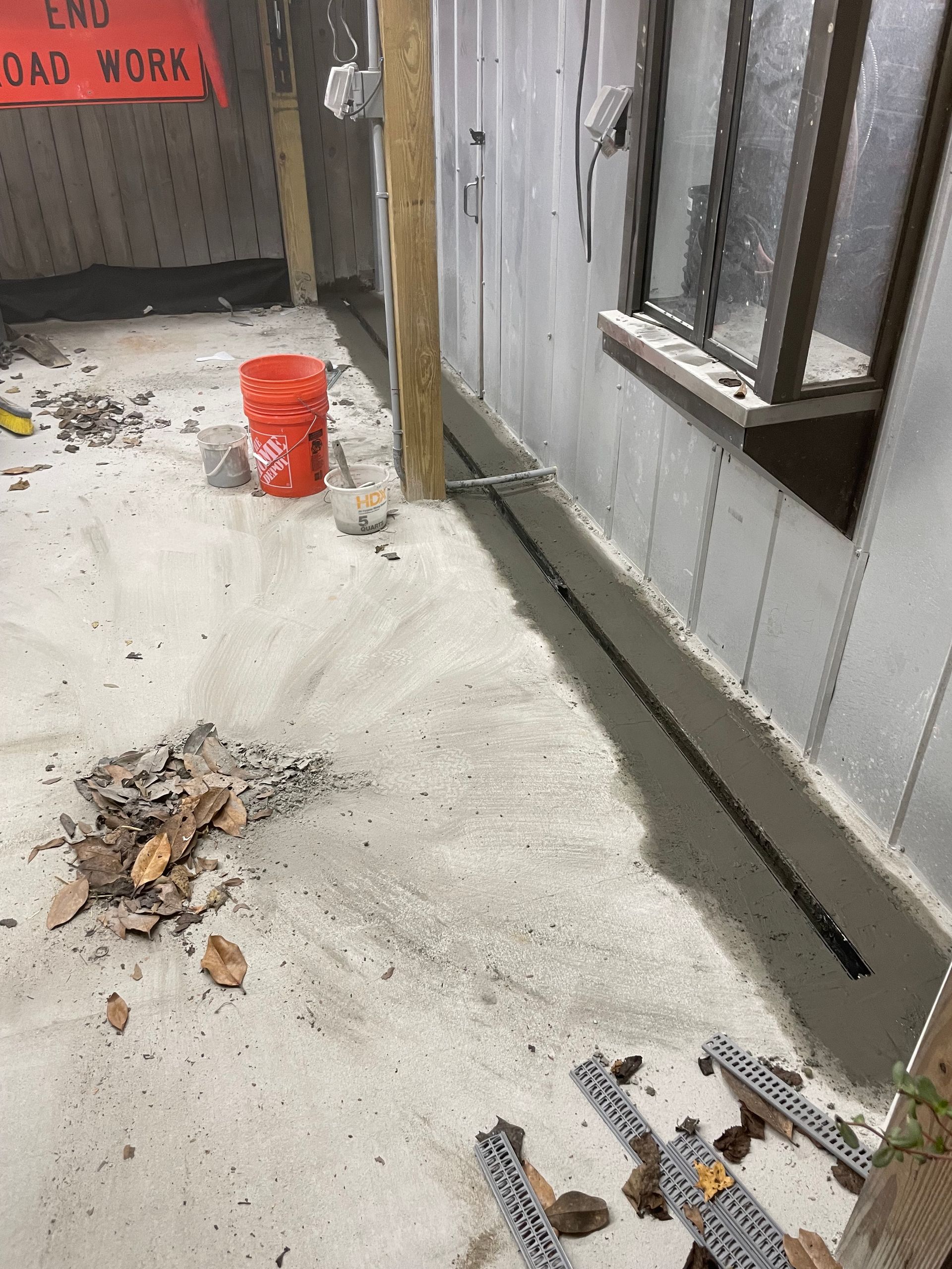 A red bucket is sitting on the ground in front of a building.