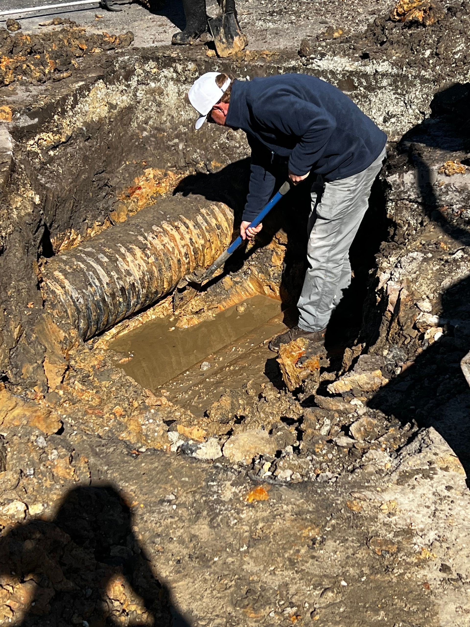A man is digging in the dirt with a shovel.