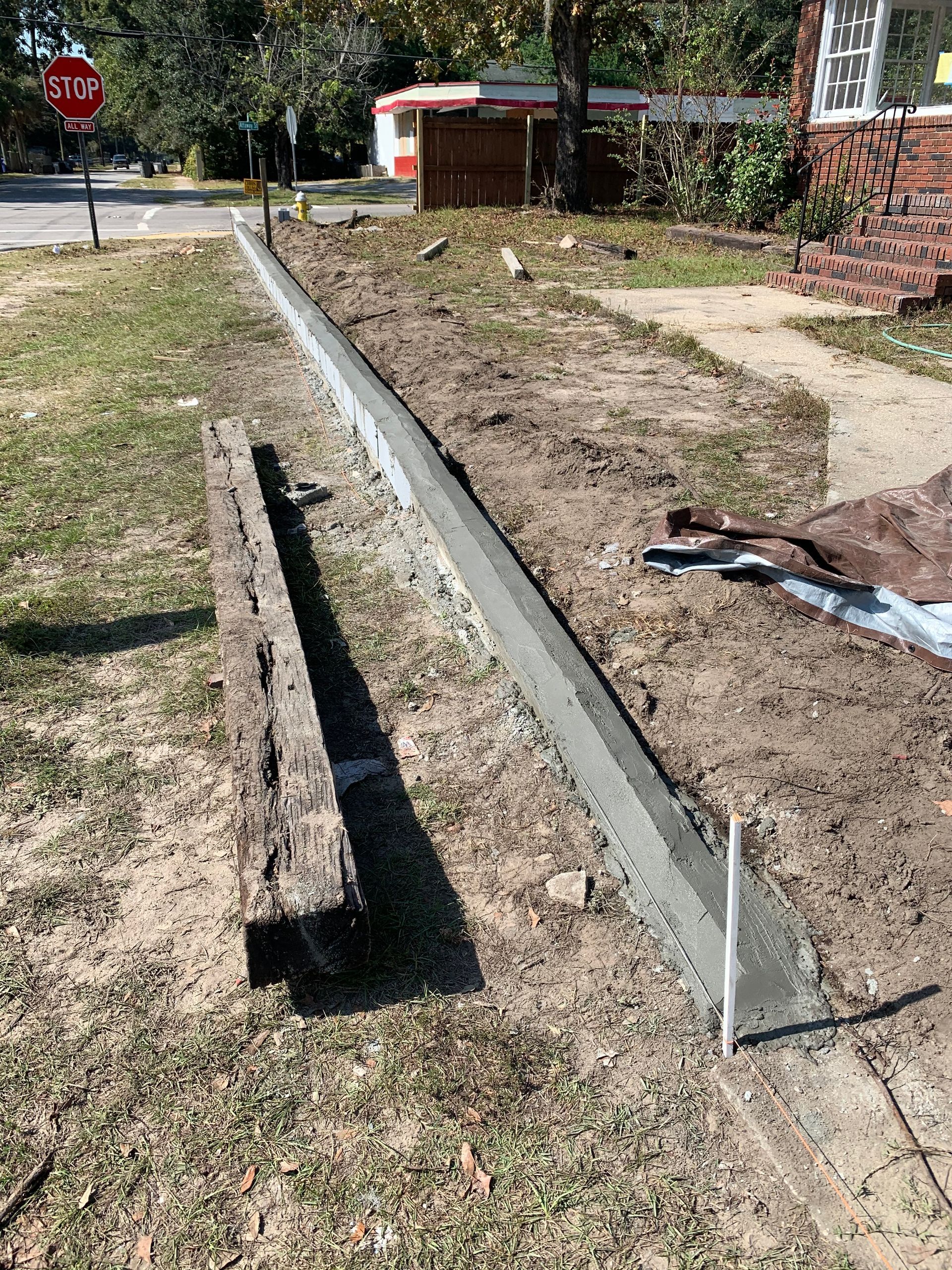A concrete curb is being built next to a stop sign.
