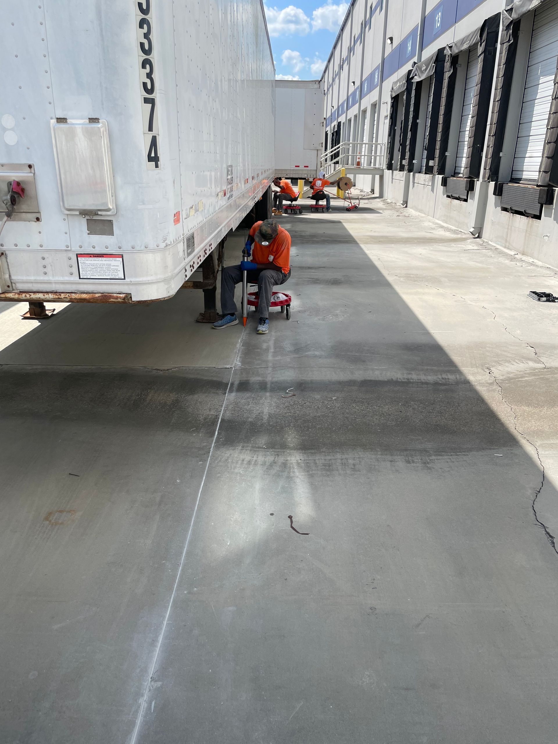 A man is working on a semi truck in a parking lot.
