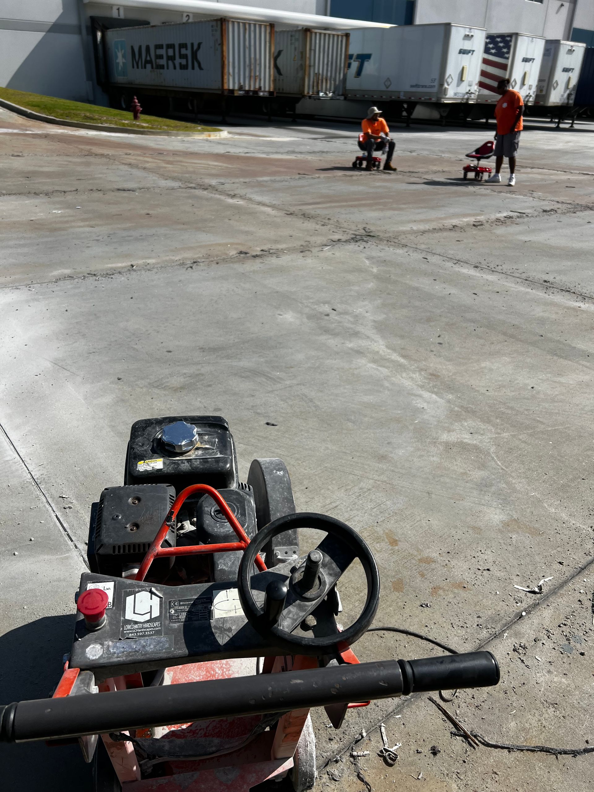 A go kart is parked in a parking lot with a maersk truck in the background