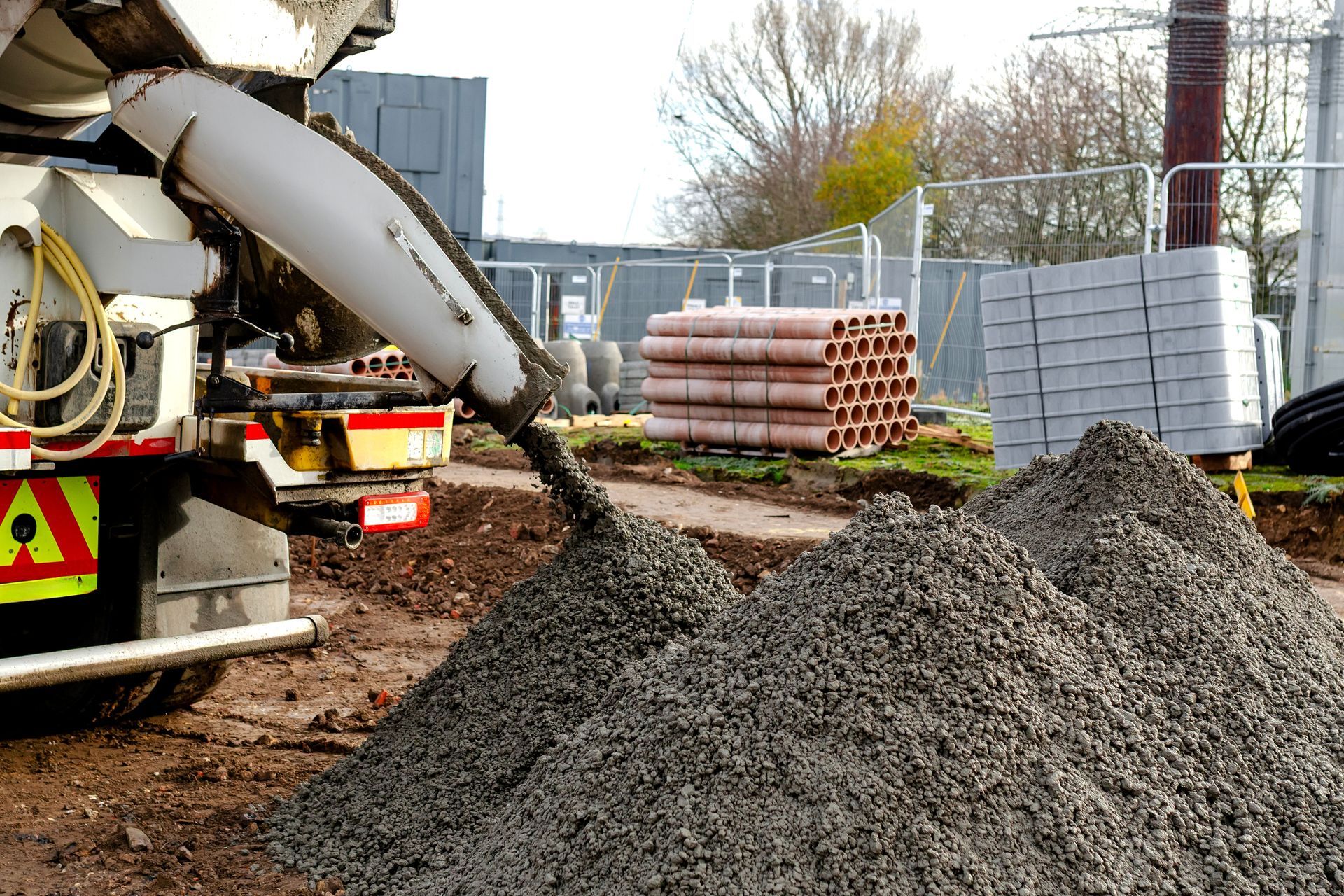A truck is unloading a semi-dry concrete mix into a ground pile at the site. A truck is unloading a semi-dry concrete mix into a ground pile at the site.