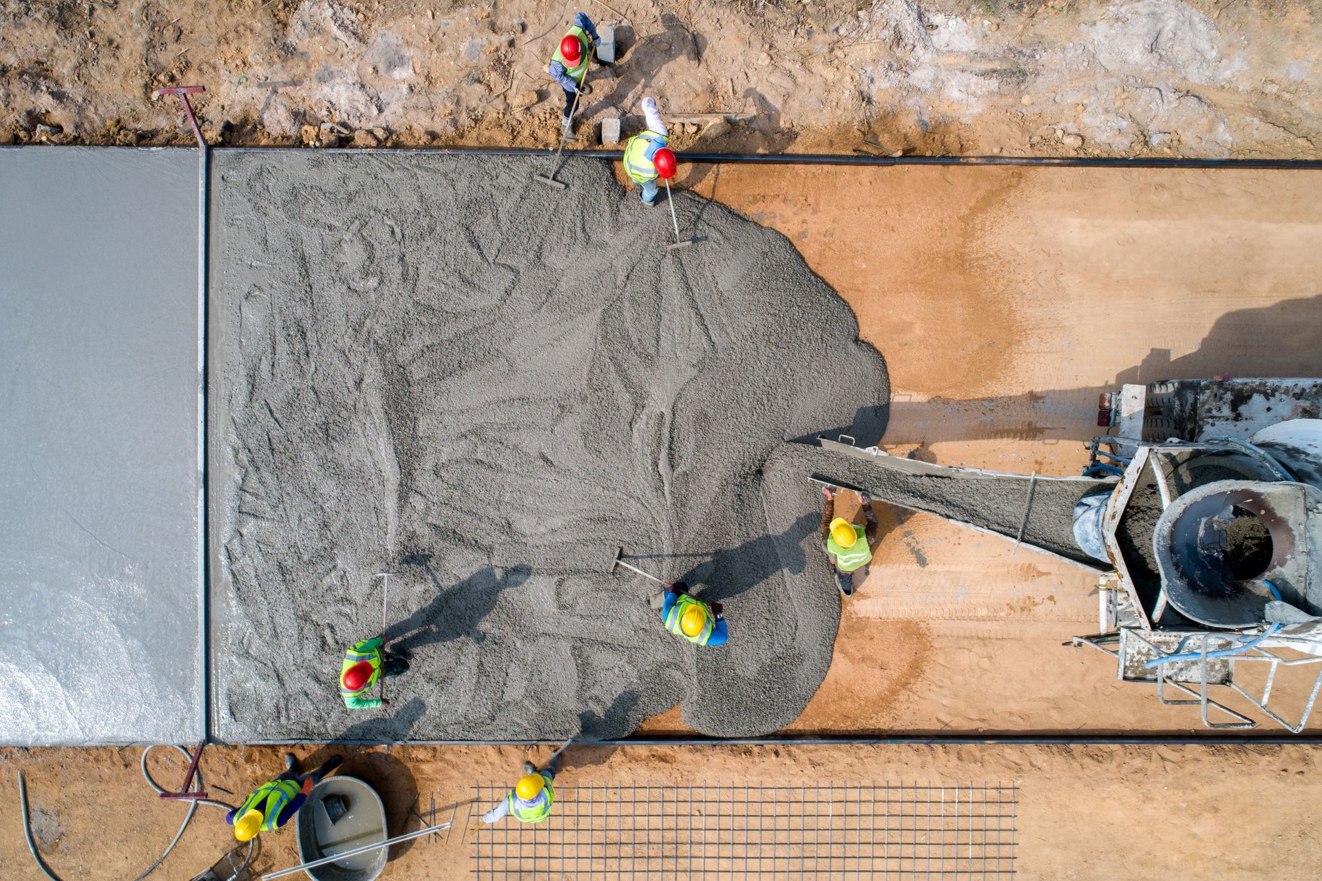 A construction worker pouring a wet concrete at road construction site.