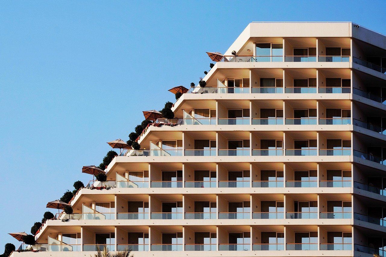 The exterior of a hotel with many balconies and umbrellas.