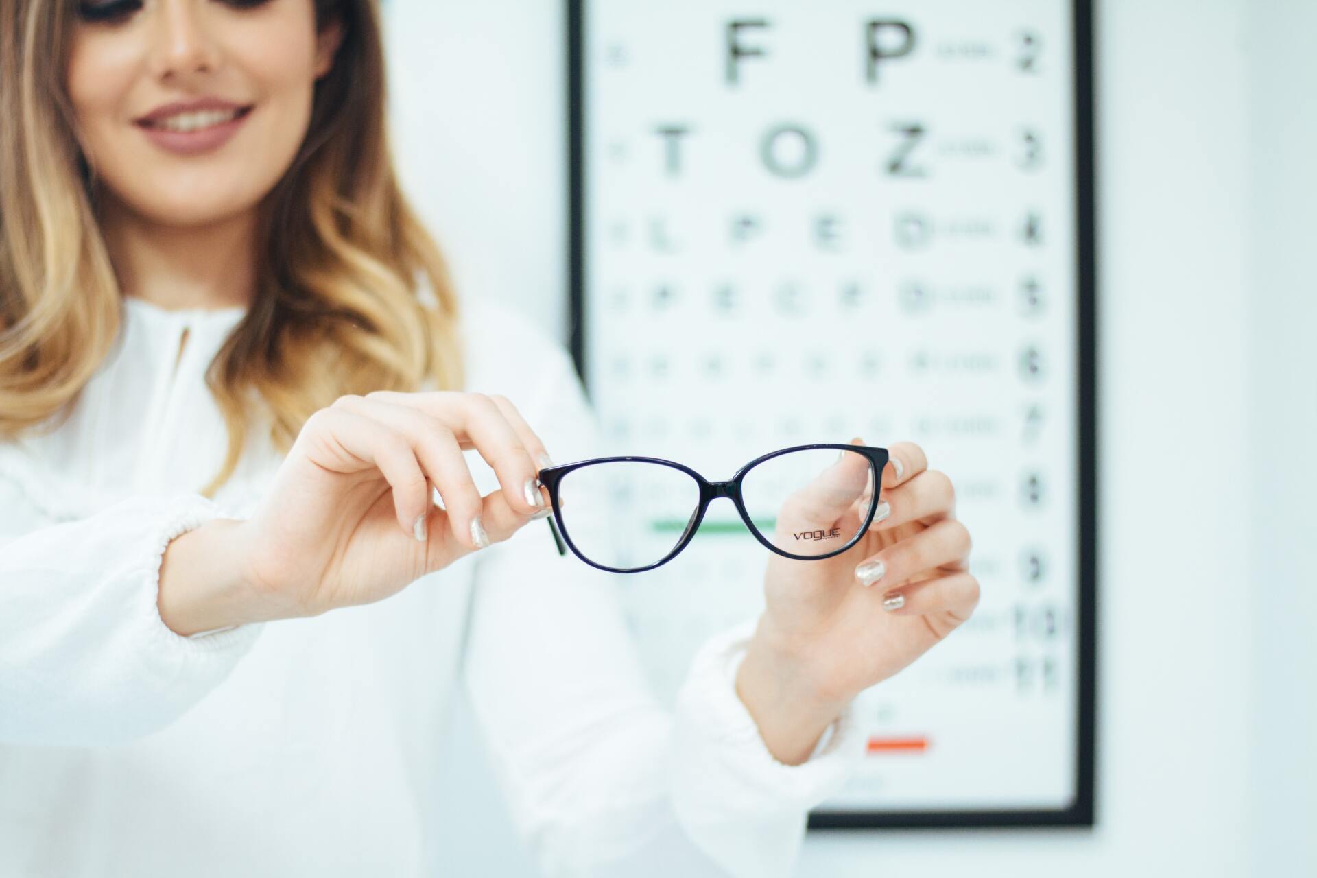 Woman holding glasses— Optometrist in Banora Point, NSW